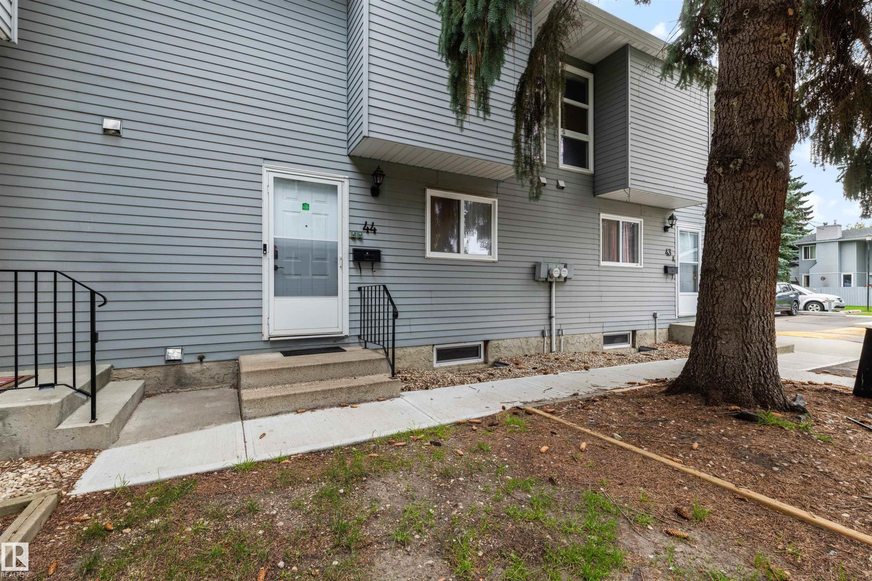 Gray horizontal siding exterior with multiple windows and a mature tree - #44 1415 62 St Nw, Edmonton, AB - Outdoor With Exterior