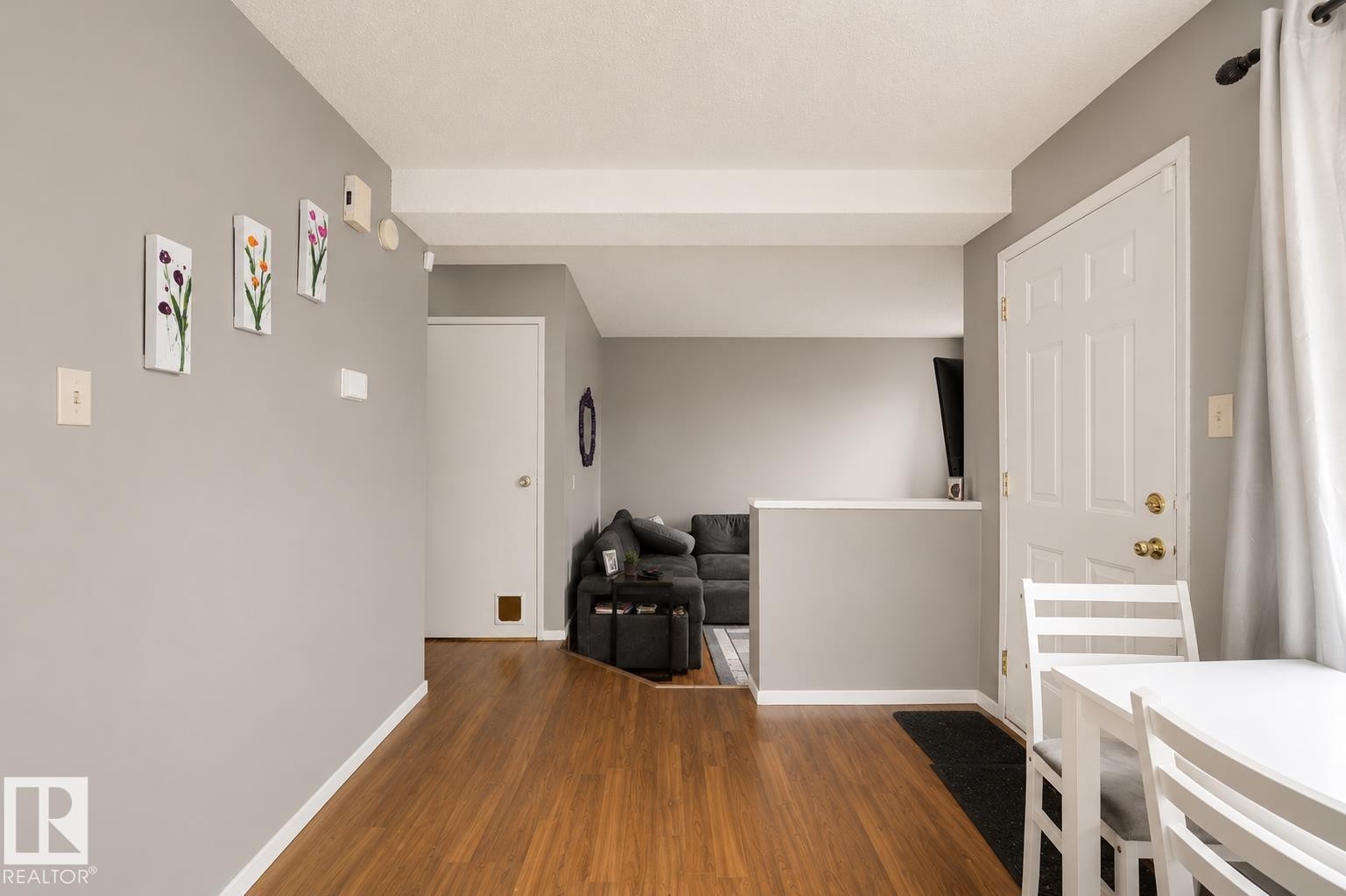 Wood-finish flooring throughout, light gray wall finishes, white trim, and white paneled interior doors - #44 1415 62 St Nw, Edmonton, AB - Indoor Photo Showing Other Room