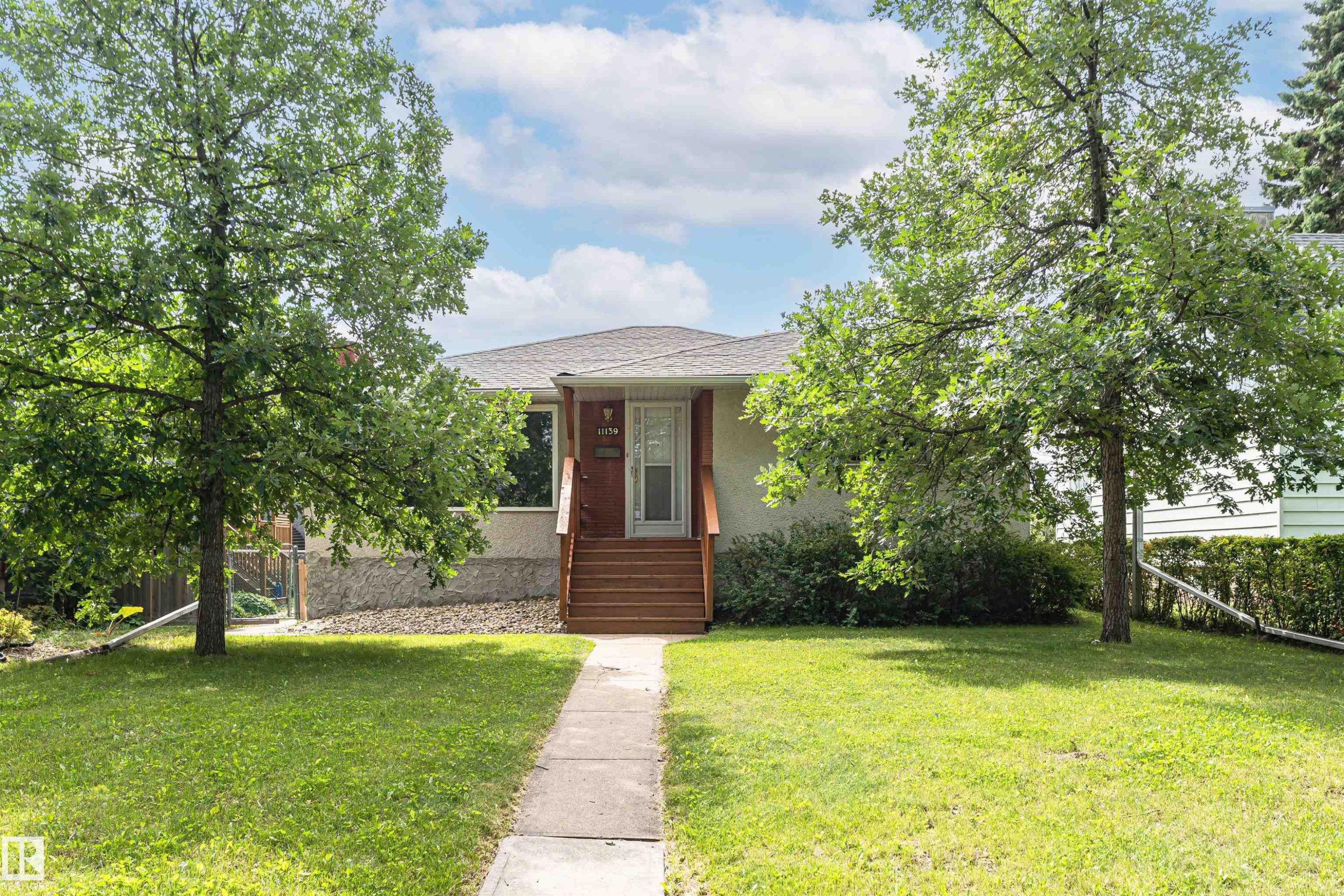 Manicured front lawn with mature trees, a concrete pathway, and wood steps leading to the main entrance - 11139 62 Avenue Nw, Edmonton, AB - Outdoor