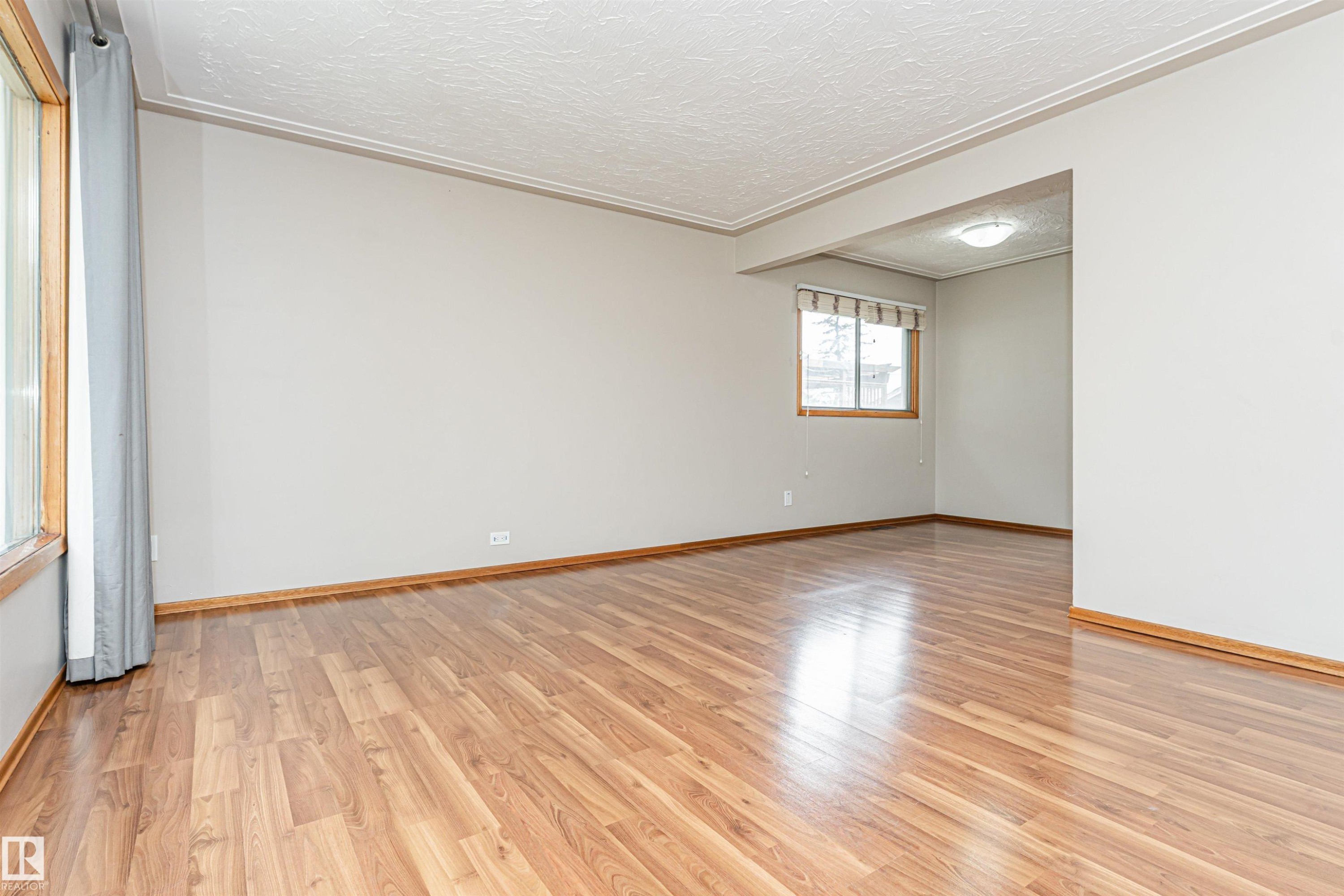 Wood-finish flooring, light neutral wall paint, crown molding, and natural light from multiple windows - 11139 62 Avenue Nw, Edmonton, AB - Indoor Photo Showing Other Room