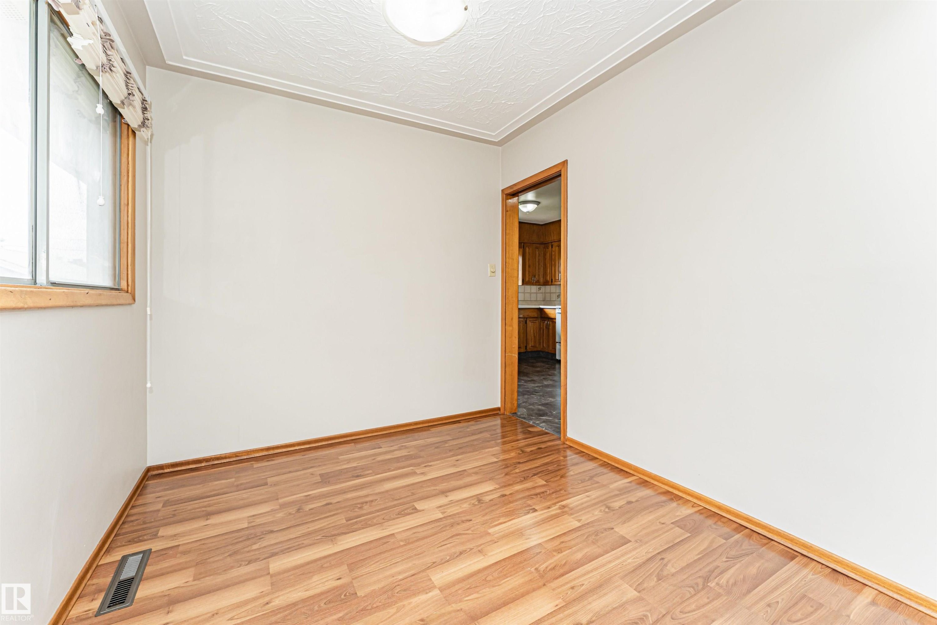 Wood-finish flooring with coordinating wood trim, crown molding, and a ceiling-mounted light fixture - 11139 62 Avenue Nw, Edmonton, AB - Indoor Photo Showing Other Room