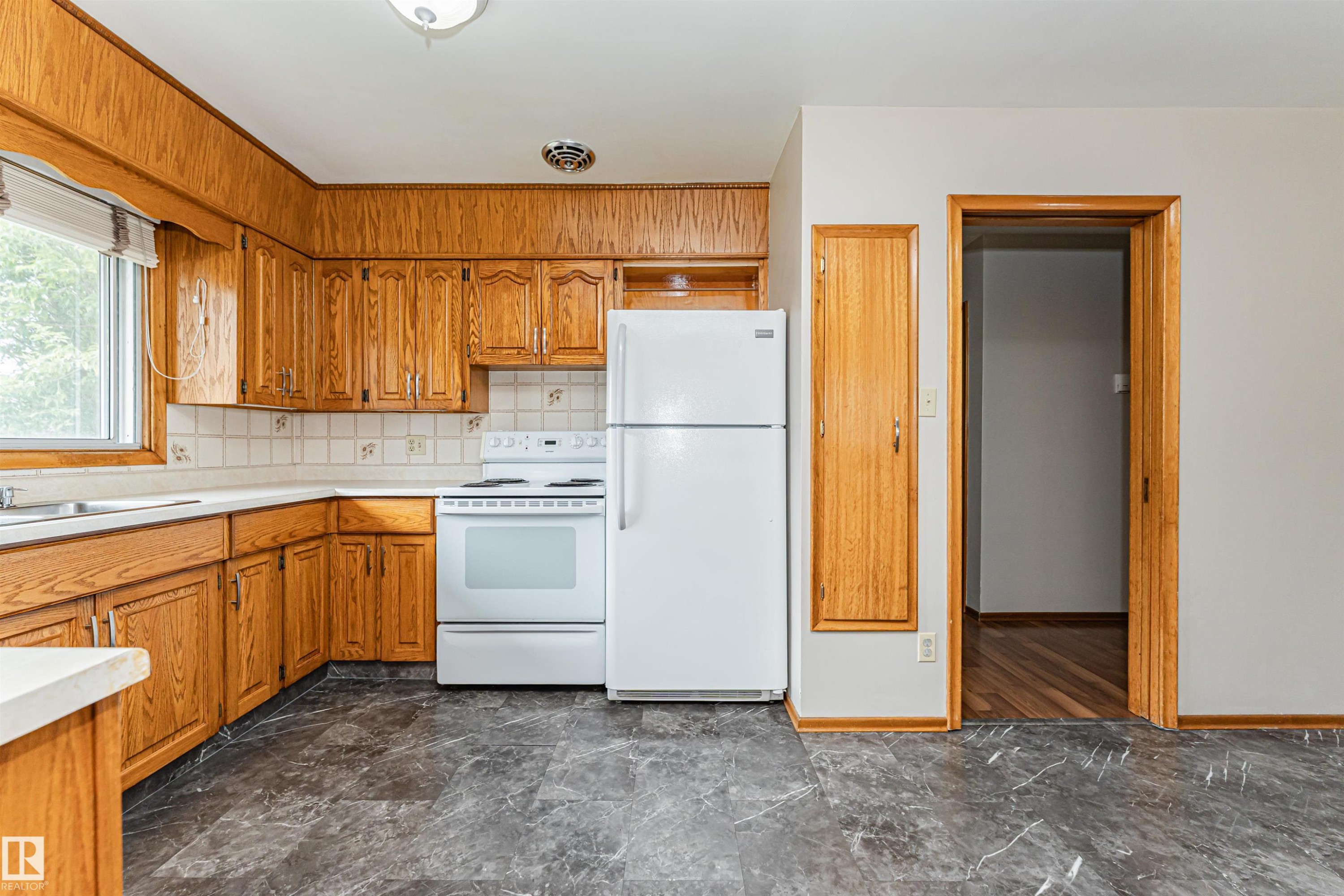 Wood cabinetry with white countertops, white tile backsplash, and dark patterned flooring - 11139 62 Avenue Nw, Edmonton, AB - Indoor Photo Showing Kitchen