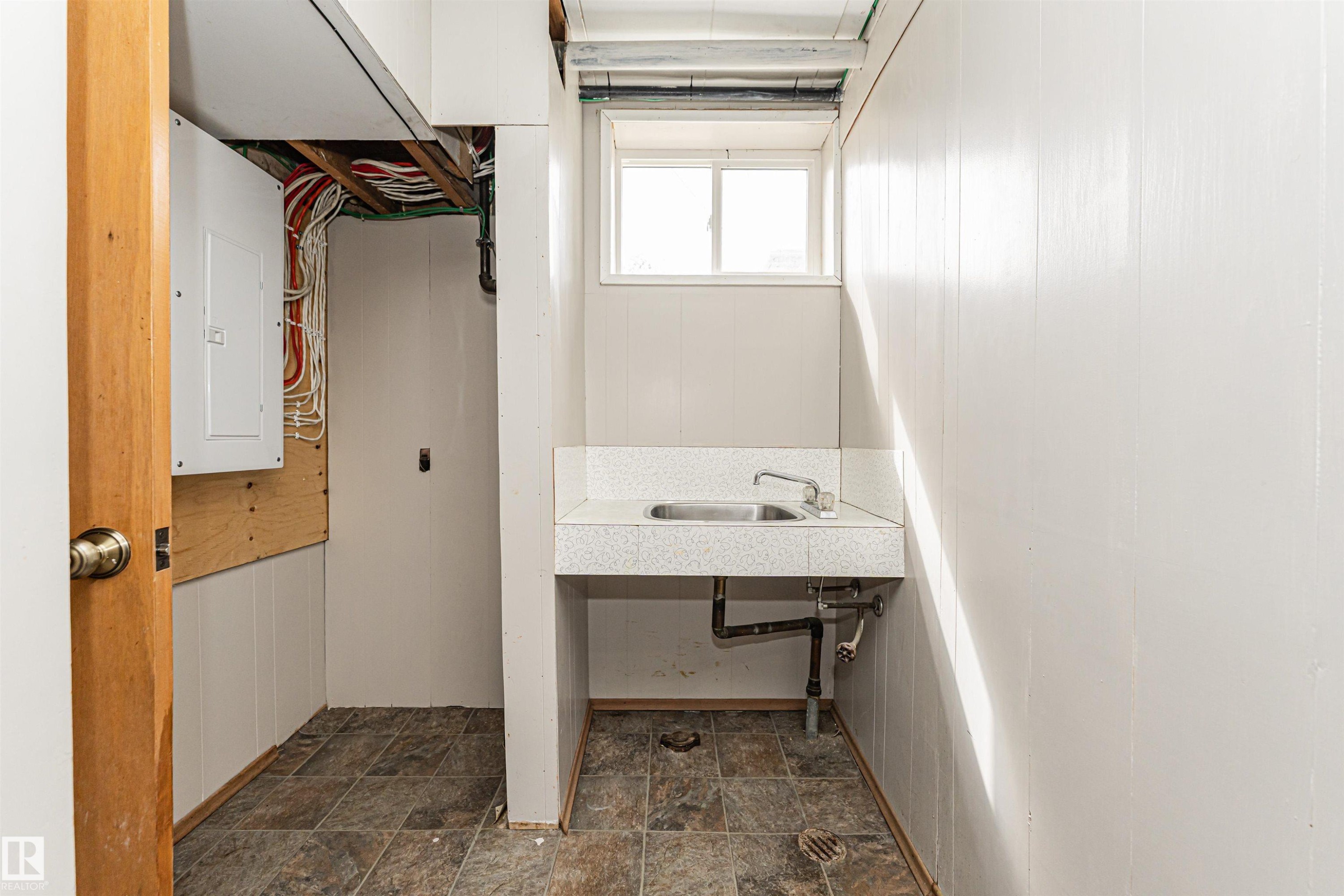 Utility room featuring a window, built-in sink, and paneling - 11139 62 Avenue Nw, Edmonton, AB - Indoor