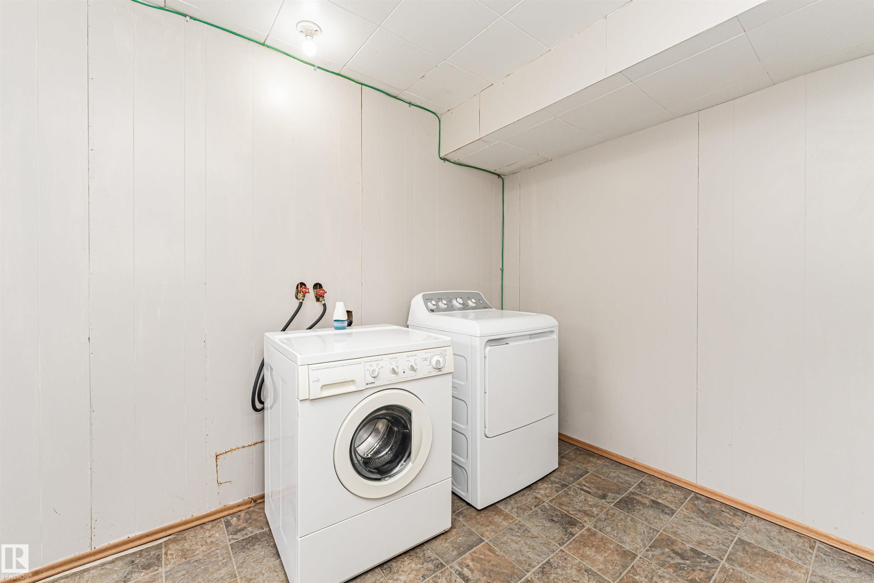 Laundry area featuring panel wall finishes, a drop ceiling, and patterned floor tiling - 11139 62 Avenue Nw, Edmonton, AB - Indoor Photo Showing Laundry Room