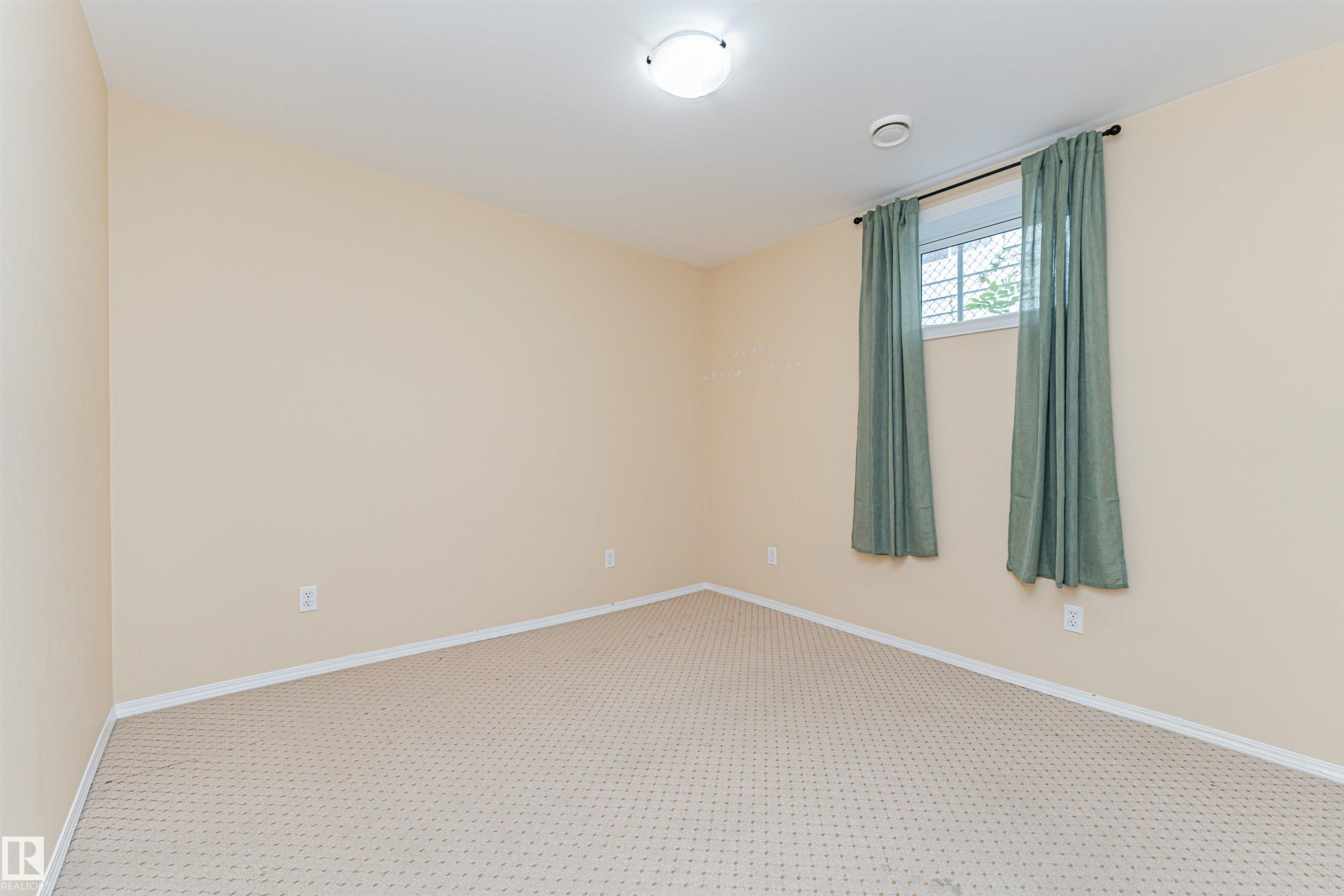 Neutral wall paint with carpeted flooring, featuring a window with security bars - 11139 62 Avenue Nw, Edmonton, AB - Indoor Photo Showing Other Room