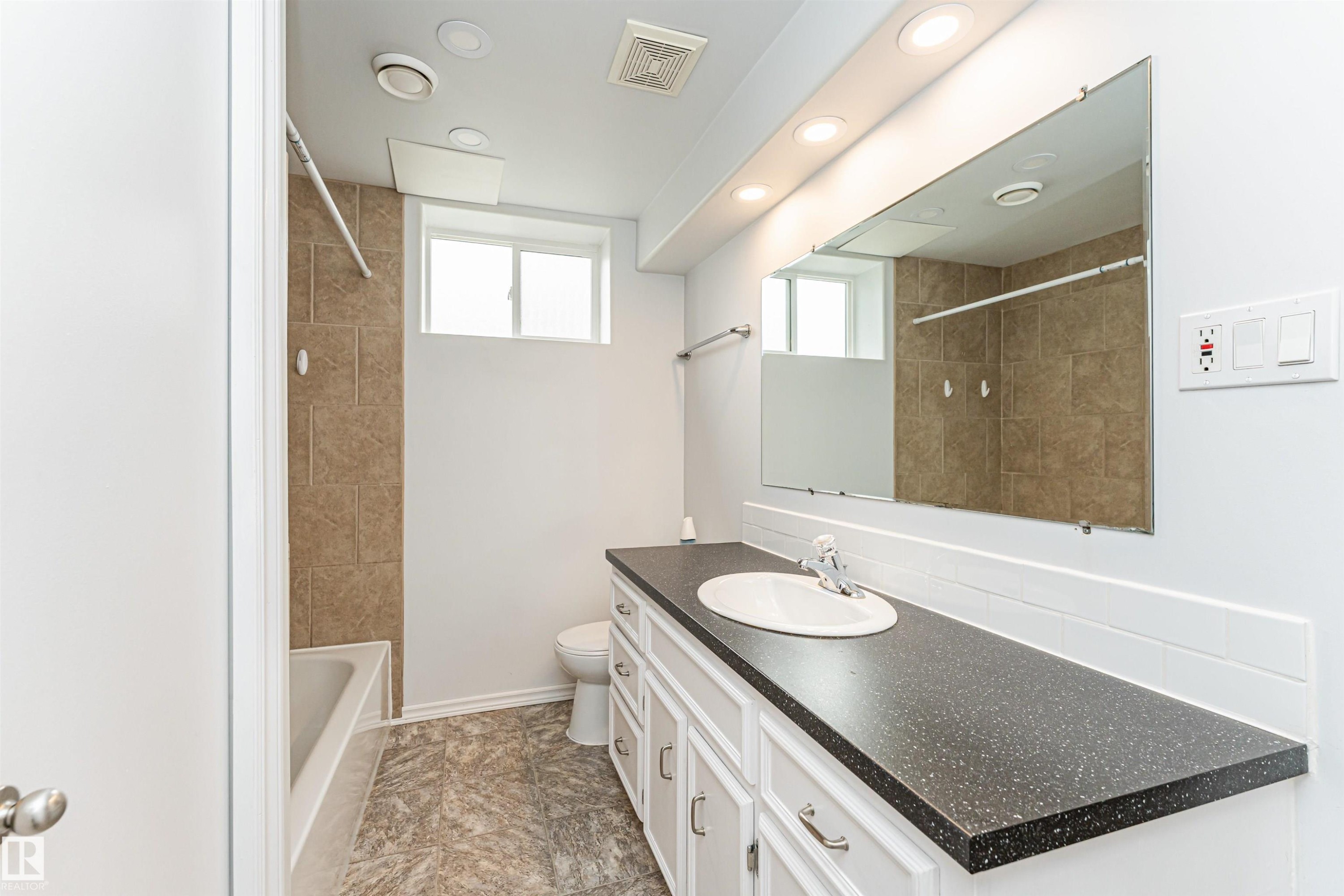 Vanity with integrated sink, white cabinetry, and dark speckled countertop - 11139 62 Avenue Nw, Edmonton, AB - Indoor Photo Showing Bathroom
