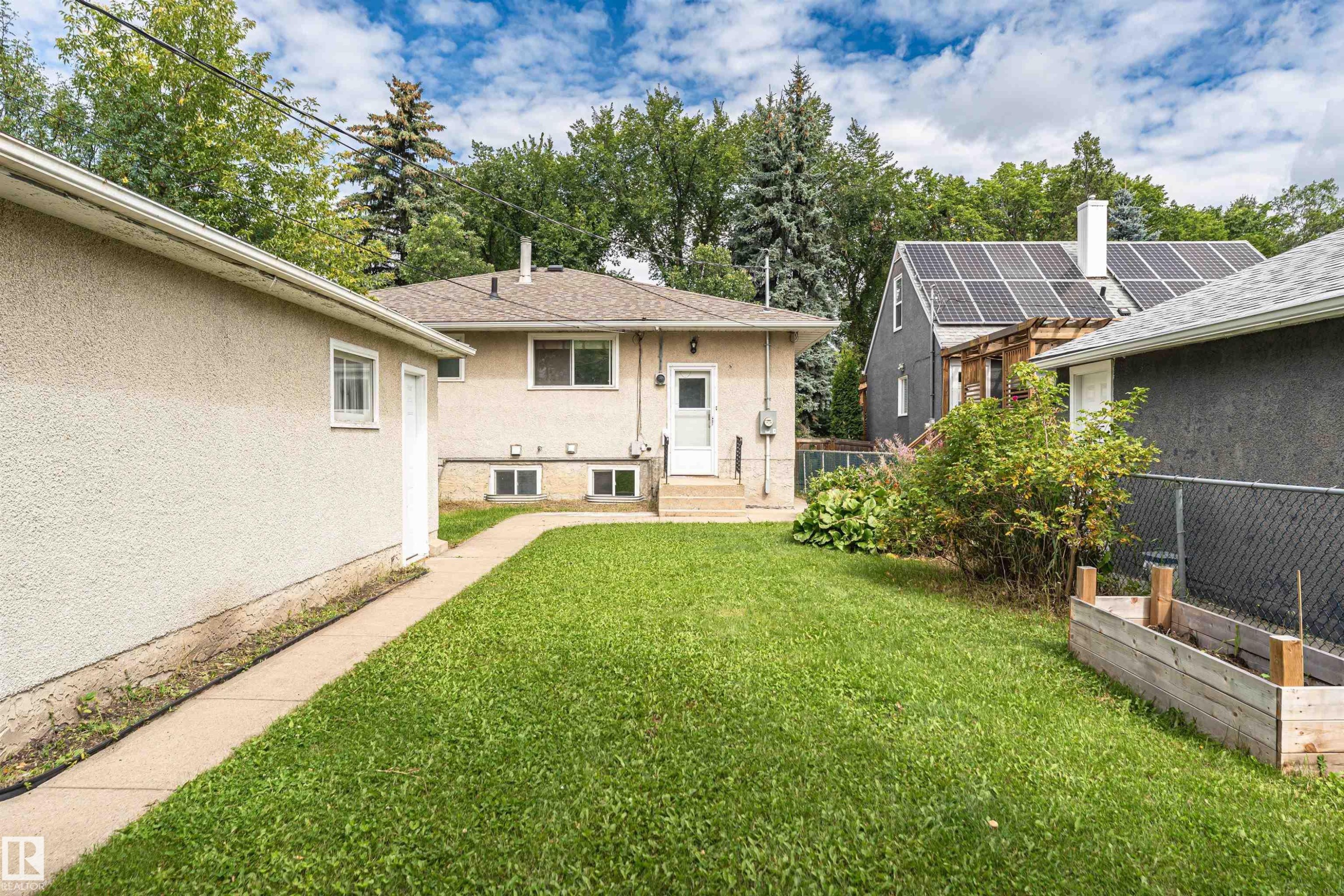 Expansive rear yard with a concrete pathway leading to the stucco exterior - 11139 62 Avenue Nw, Edmonton, AB - Outdoor