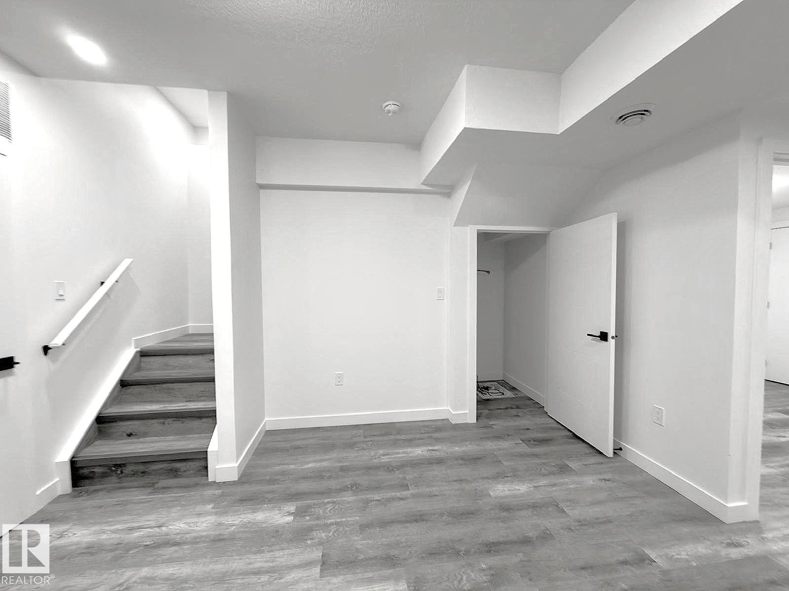 Wood-finish flooring, white walls, and a staircase with a white handrail - 1312 35 Street Nw, Edmonton, AB