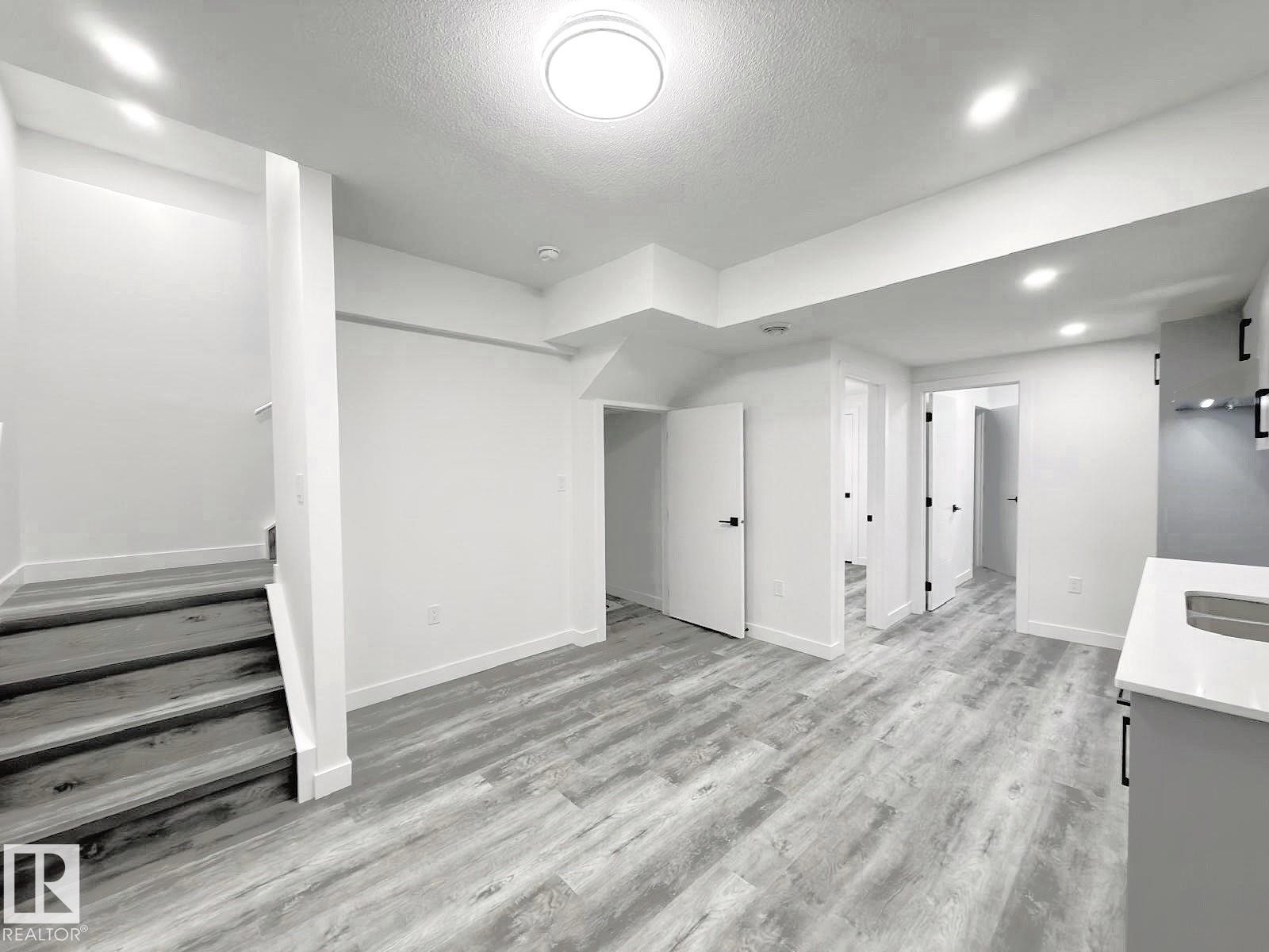 Light wood-finish flooring throughout, recessed lighting, and a contemporary flush-mount ceiling fixture - 1312 35 Street Nw, Edmonton, AB