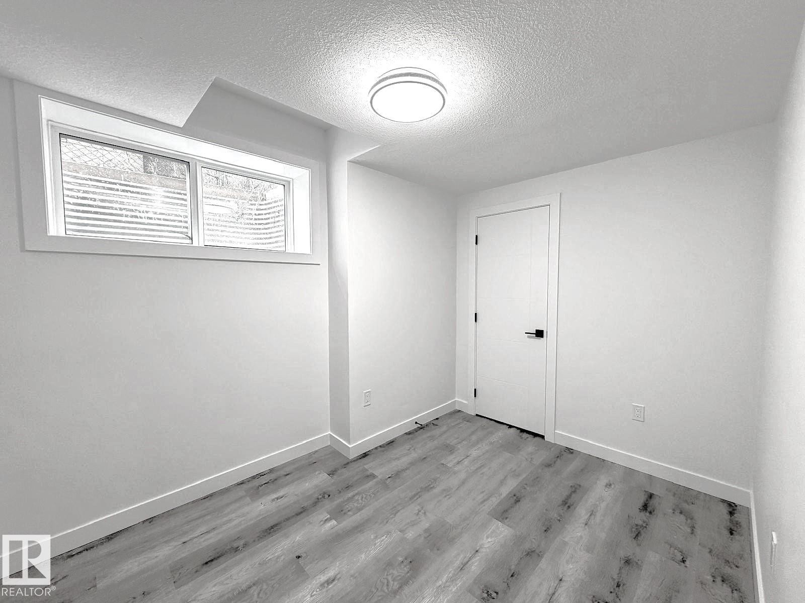 Recessed window, ceiling-mounted light fixture, wood-finish flooring, white painted walls, white door with black hardware - 1312 35 Street Nw, Edmonton, AB