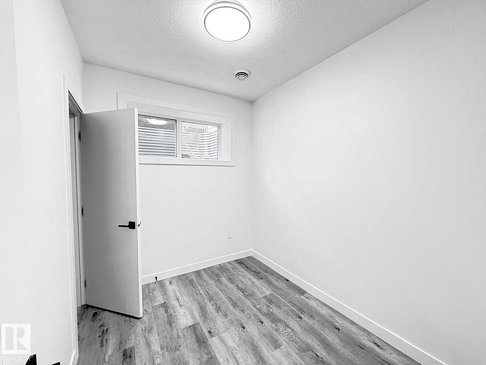 Recessed window with white blinds, wood-finish flooring, white walls, and a flush mount ceiling light - 1312 35 Street Nw, Edmonton, AB