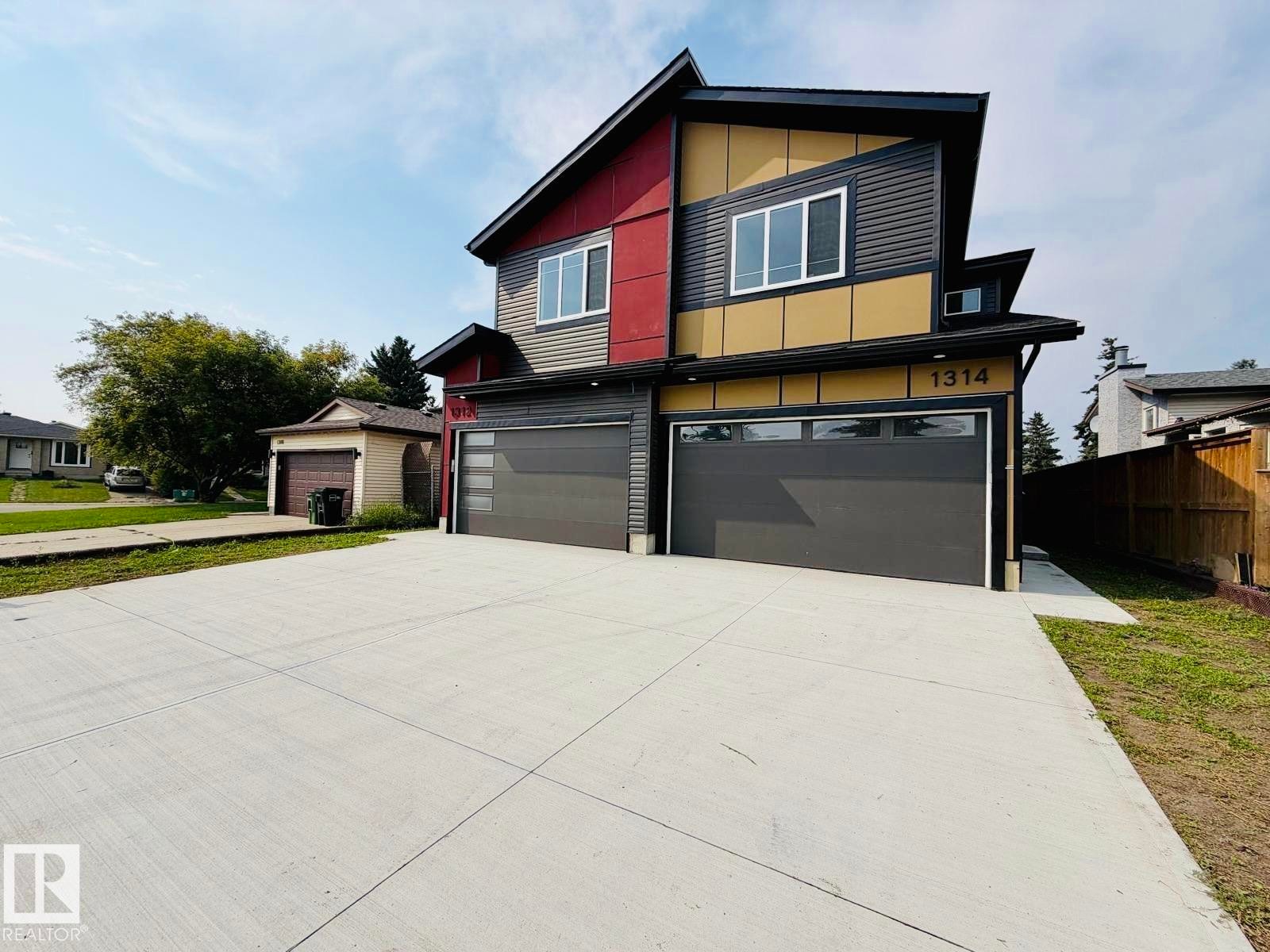 Modern exterior with multi-toned siding, dark garage doors with frosted glass panels, and a concrete driveway - 1312 35 Street Nw, Edmonton, AB