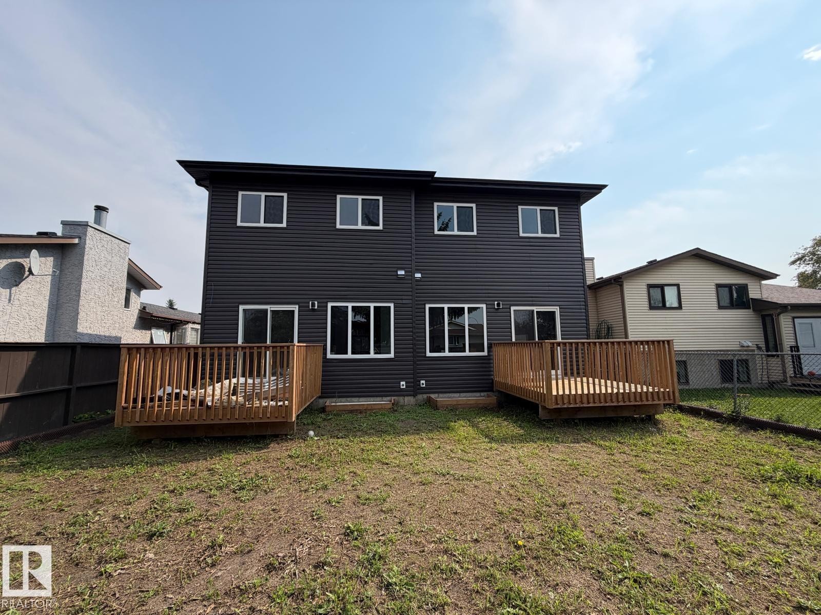 Black horizontal siding with white trim windows and two separate wood decks - 1312 35 Street Nw, Edmonton, AB