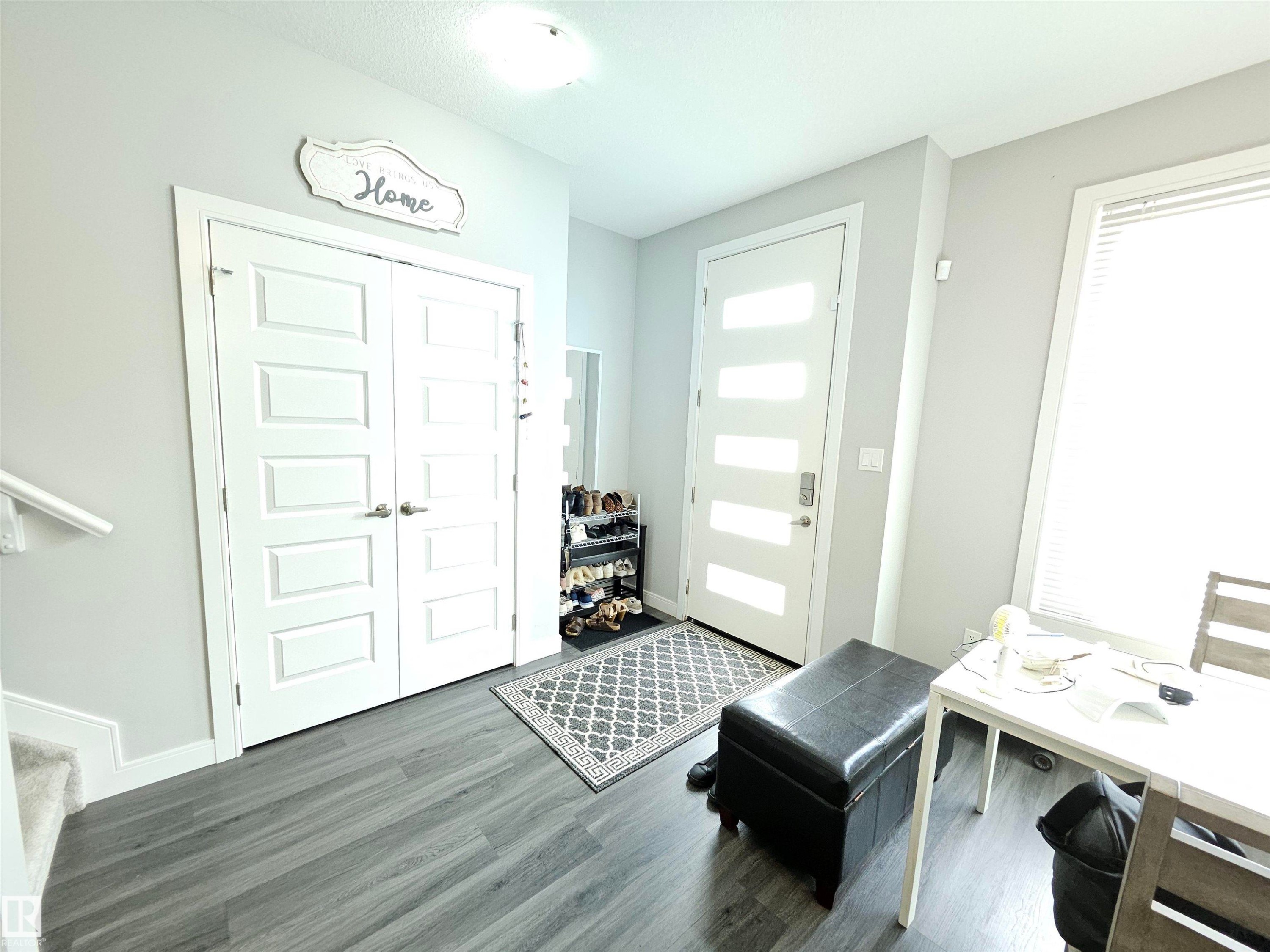 Modern entry door with frosted glass panels, wood-finish flooring, and light gray wall paint - 15212 98 Avenue Nw, Edmonton, AB - Indoor