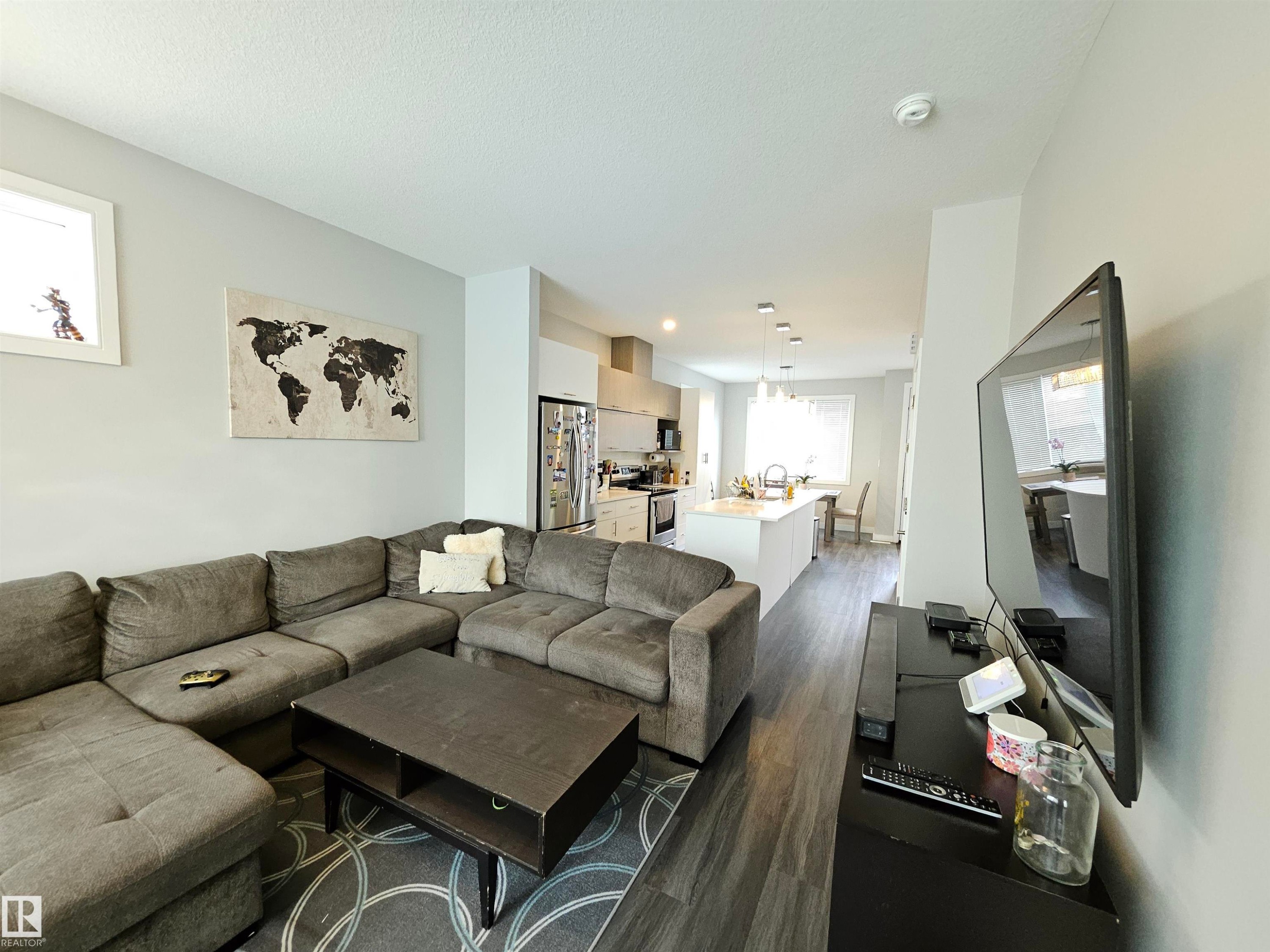 Open-concept living area with wood-finish flooring, recessed lighting, and a kitchen featuring a large island with pendant lights - 15212 98 Avenue Nw, Edmonton, AB - Indoor Photo Showing Living Room