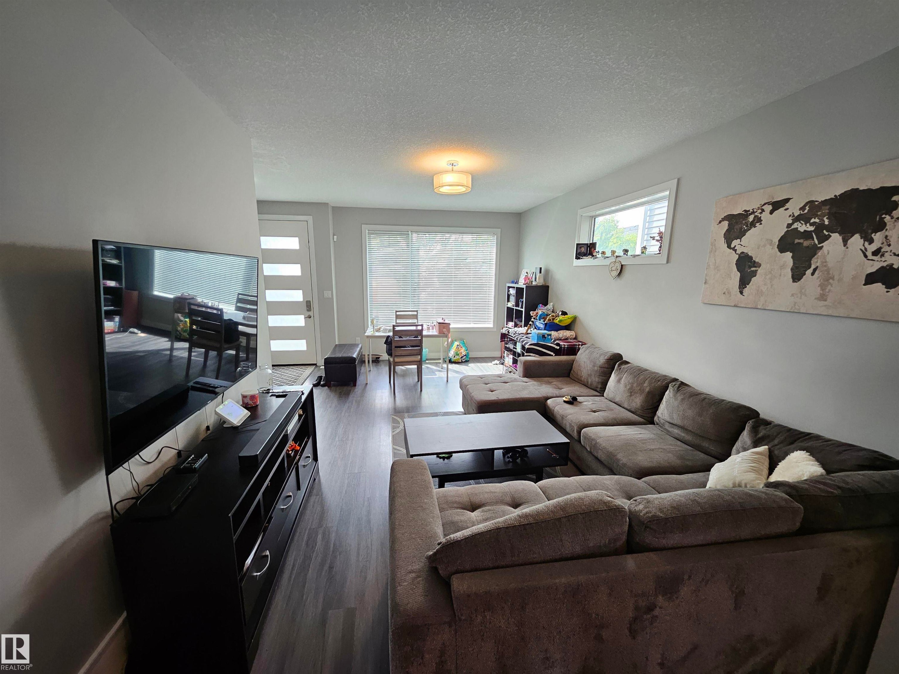 Spacious open-concept living area featuring wood-finish flooring, recessed lighting, and large windows - 15212 98 Avenue Nw, Edmonton, AB - Indoor Photo Showing Living Room