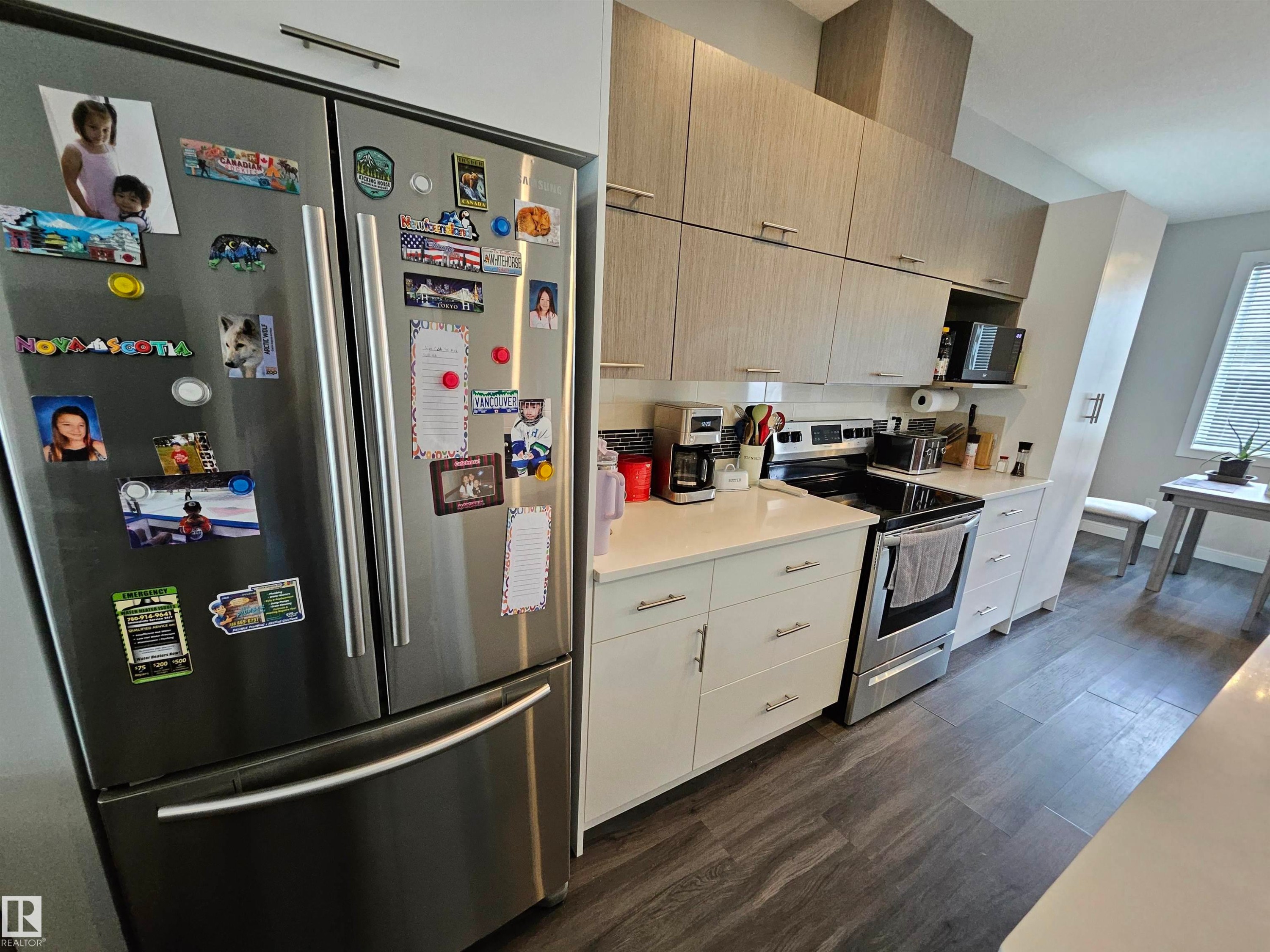 Stainless steel French door refrigerator, wood-finish flooring, white countertops, and light wood-grain upper cabinetry - 15212 98 Avenue Nw, Edmonton, AB - Indoor Photo Showing Kitchen