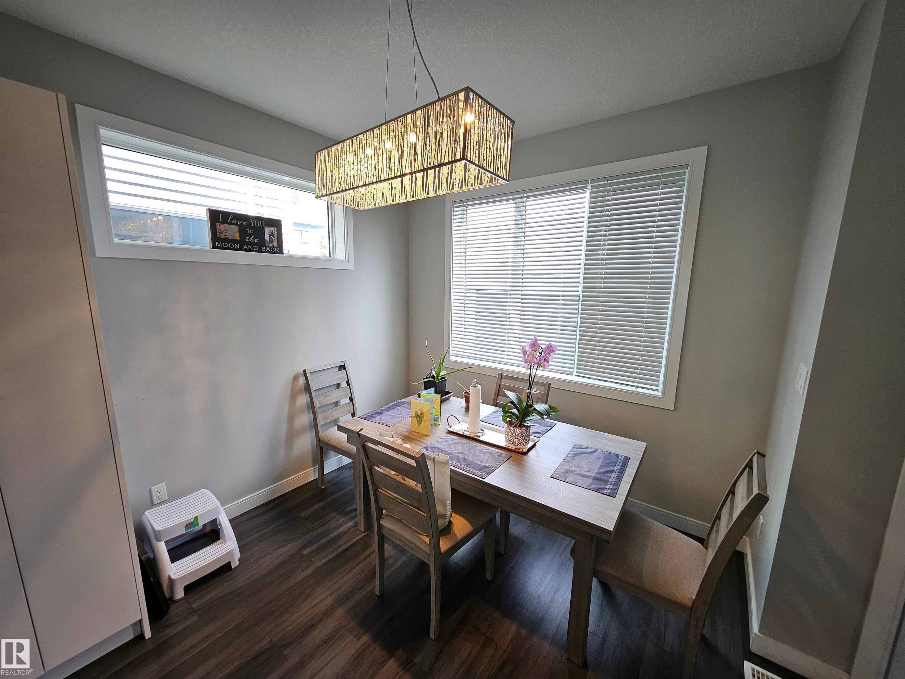 Contemporary rectangular chandelier, wood-finish flooring, and multiple windows - 15212 98 Avenue Nw, Edmonton, AB - Indoor Photo Showing Dining Room