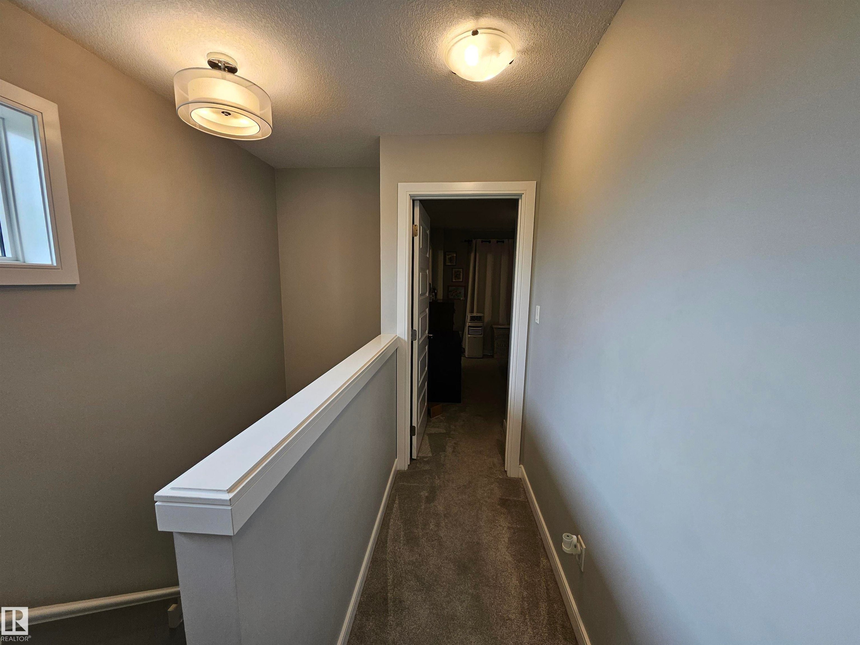 Bright hallway with crisp white wainscoting, warm ceiling-mounted lighting, and neutral wall finishes - 15212 98 Avenue Nw, Edmonton, AB - Indoor Photo Showing Other Room