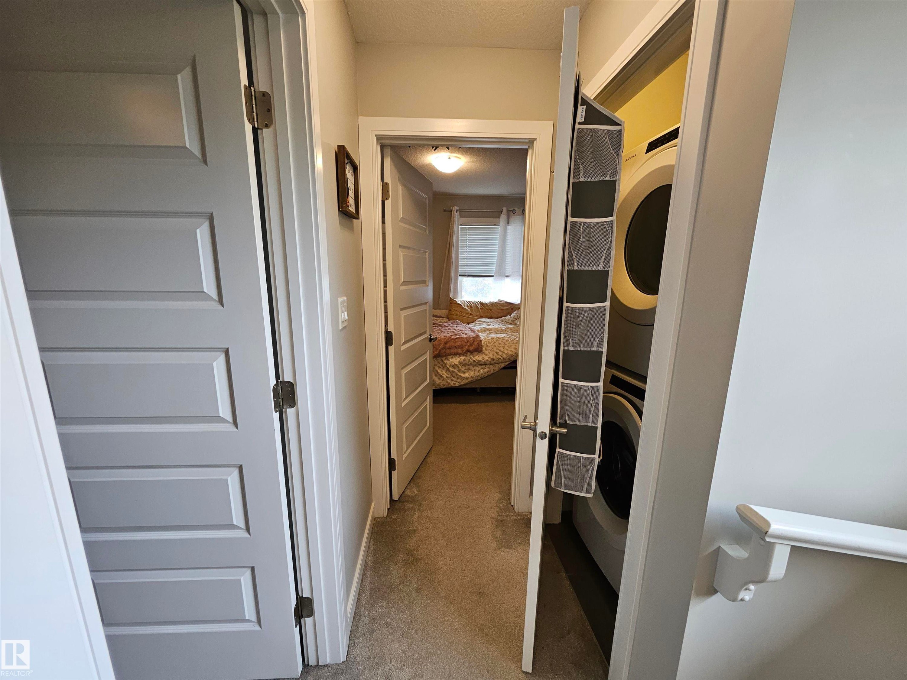 Integrated laundry closet with stacked washer and dryer - 15212 98 Avenue Nw, Edmonton, AB - Indoor Photo Showing Other Room