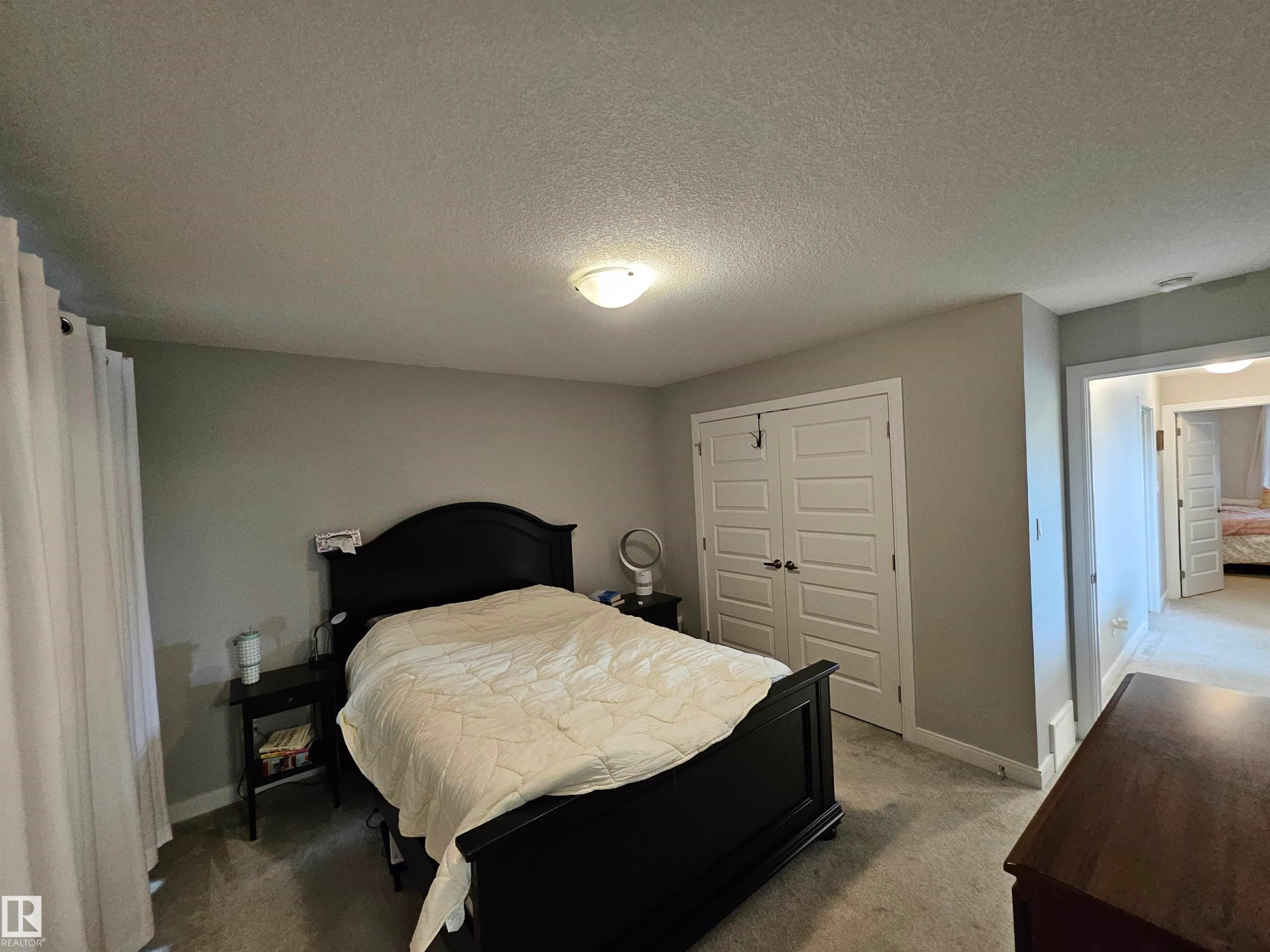 Spacious primary bedroom featuring a black four-poster bed frame, dual closets with six-panel doors, carpet flooring, and recessed ceiling lighting - 15212 98 Avenue Nw, Edmonton, AB - Indoor Photo Showing Bedroom