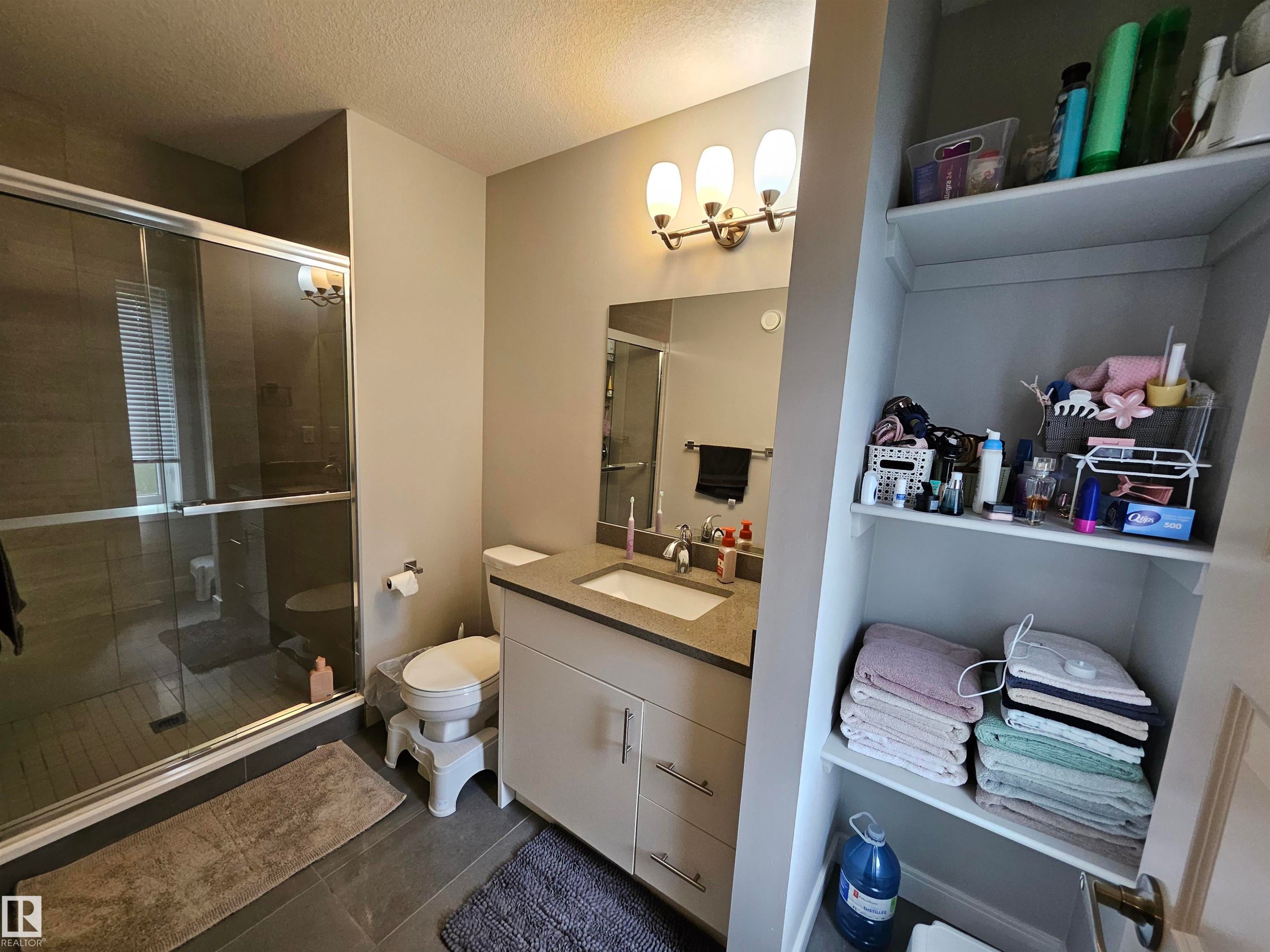 Spa-inspired primary bathroom featuring a frameless glass-enclosed shower with tile surround, dual-sink vanity with ample countertop storage, and recessed lighting - 15212 98 Avenue Nw, Edmonton, AB - Indoor Photo Showing Bathroom