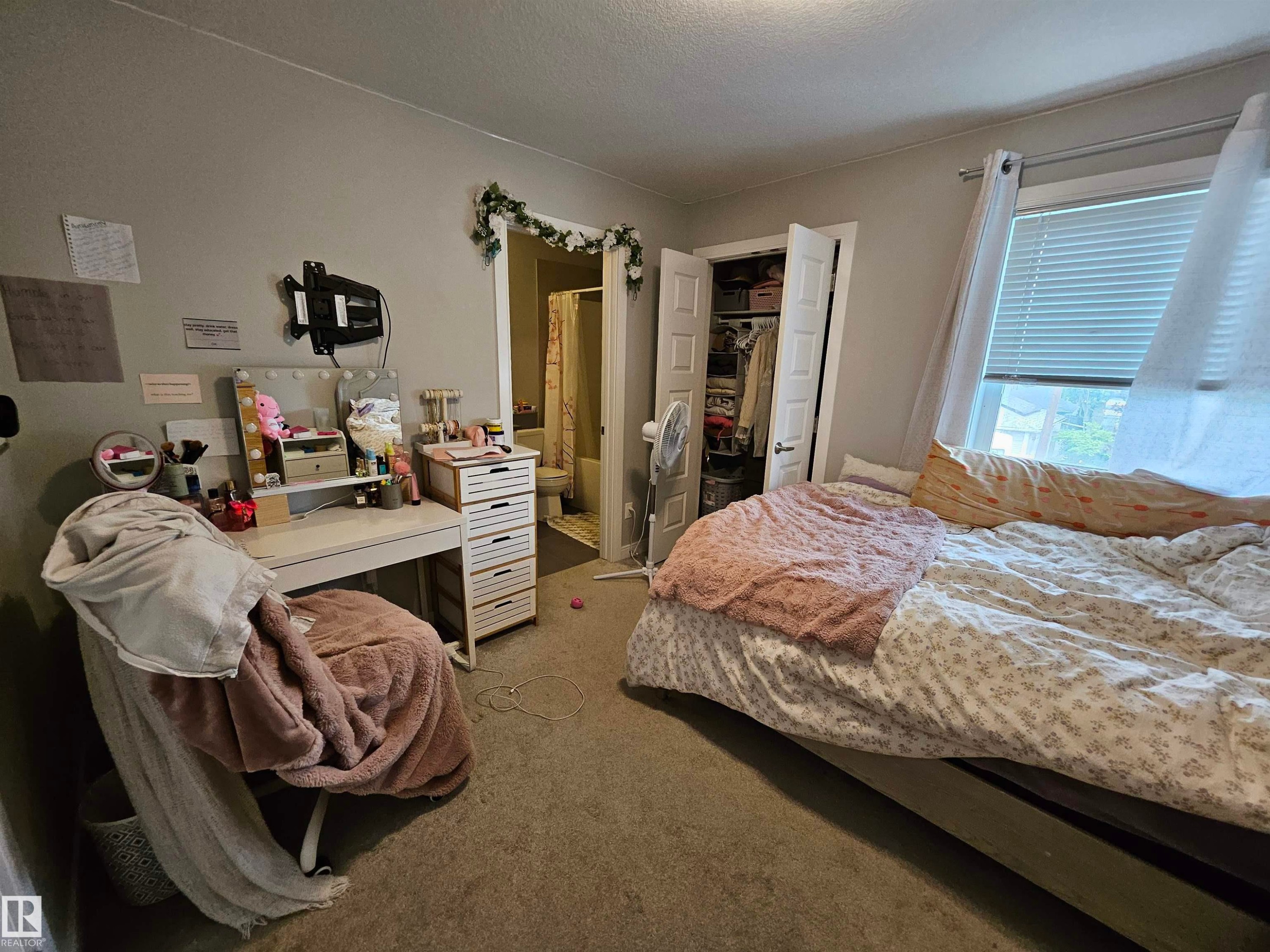 Carpeted room featuring a window with blinds, a built-in closet with double doors, and an open doorway - 15212 98 Avenue Nw, Edmonton, AB - Indoor Photo Showing Bedroom