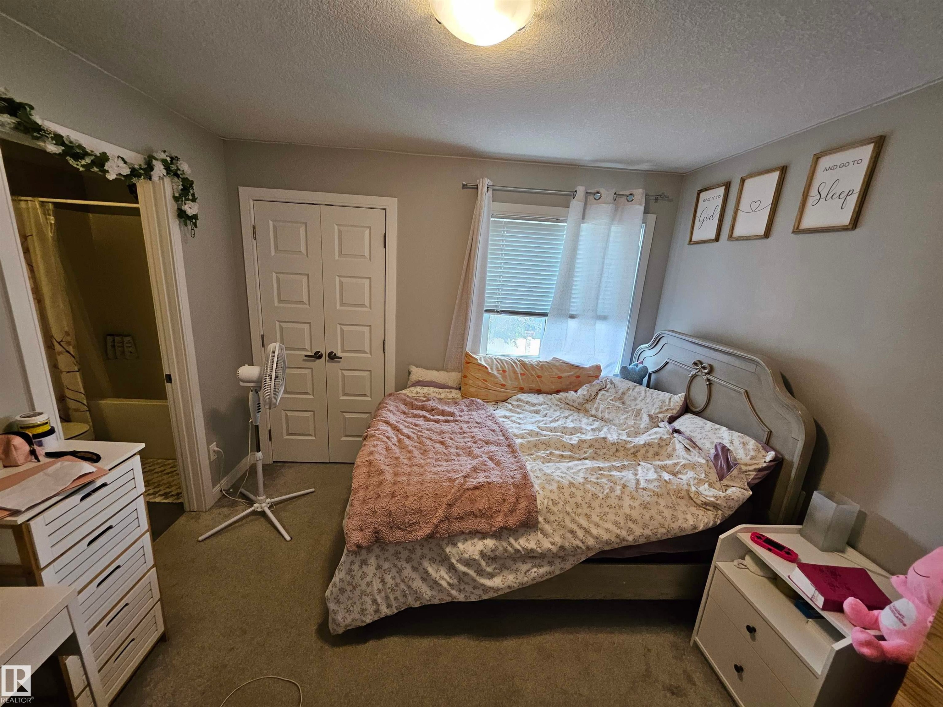 Carpeted room with a window, white blinds, and a built-in closet with bifold doors - 15212 98 Avenue Nw, Edmonton, AB - Indoor Photo Showing Bedroom