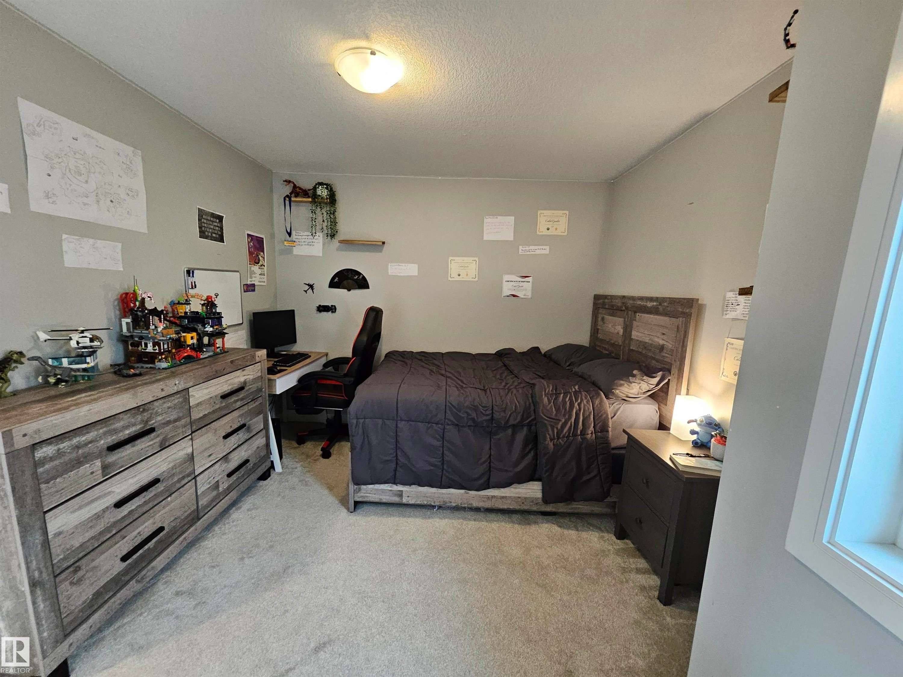 Carpeted room featuring a light fixture, a window with white trim, and a gray wall color - 15212 98 Avenue Nw, Edmonton, AB - Indoor