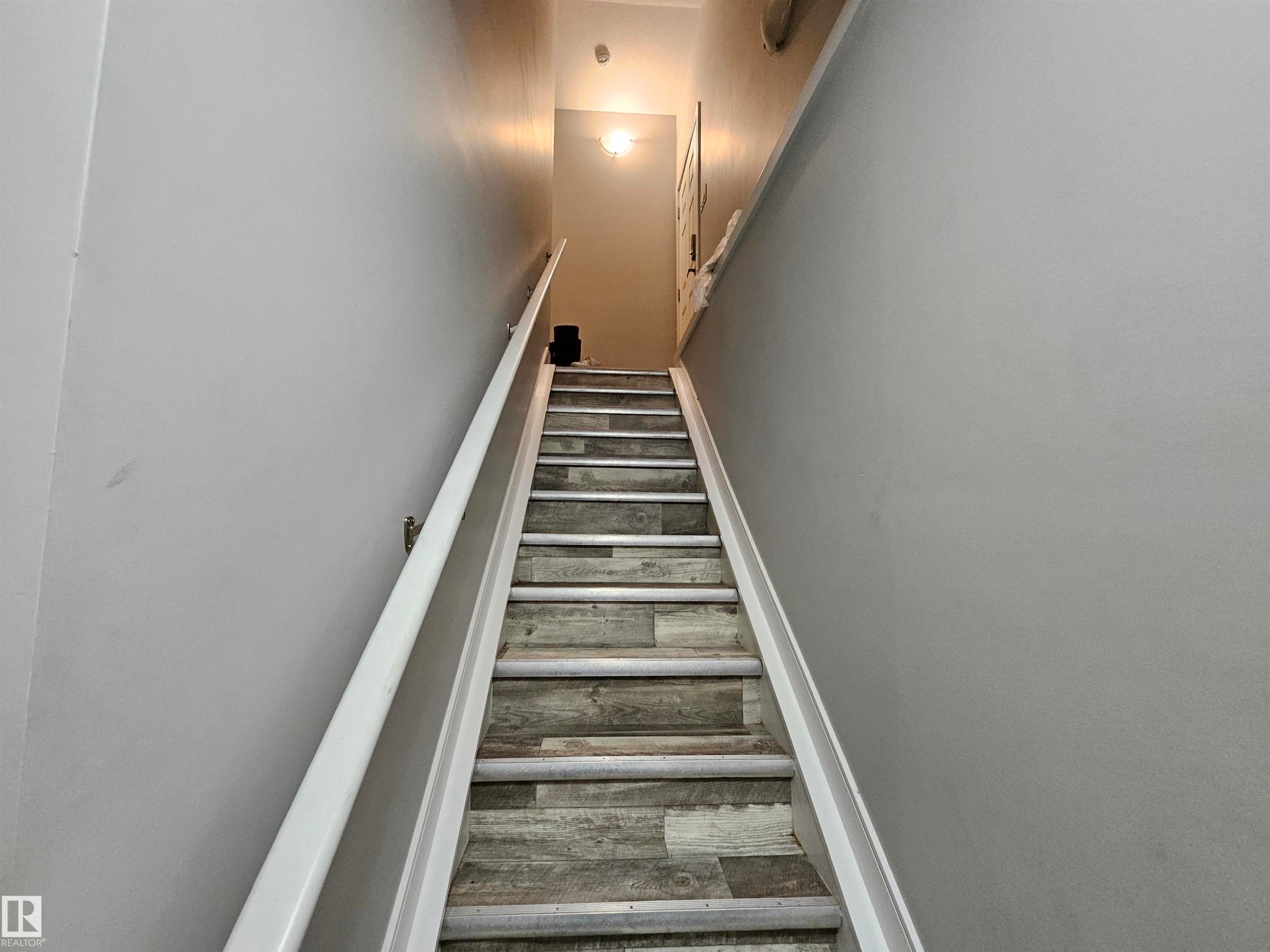 Staircase with wood-finish risers and treads, featuring a white handrail and light gray wall paint - 15212 98 Avenue Nw, Edmonton, AB - Indoor Photo Showing Other Room