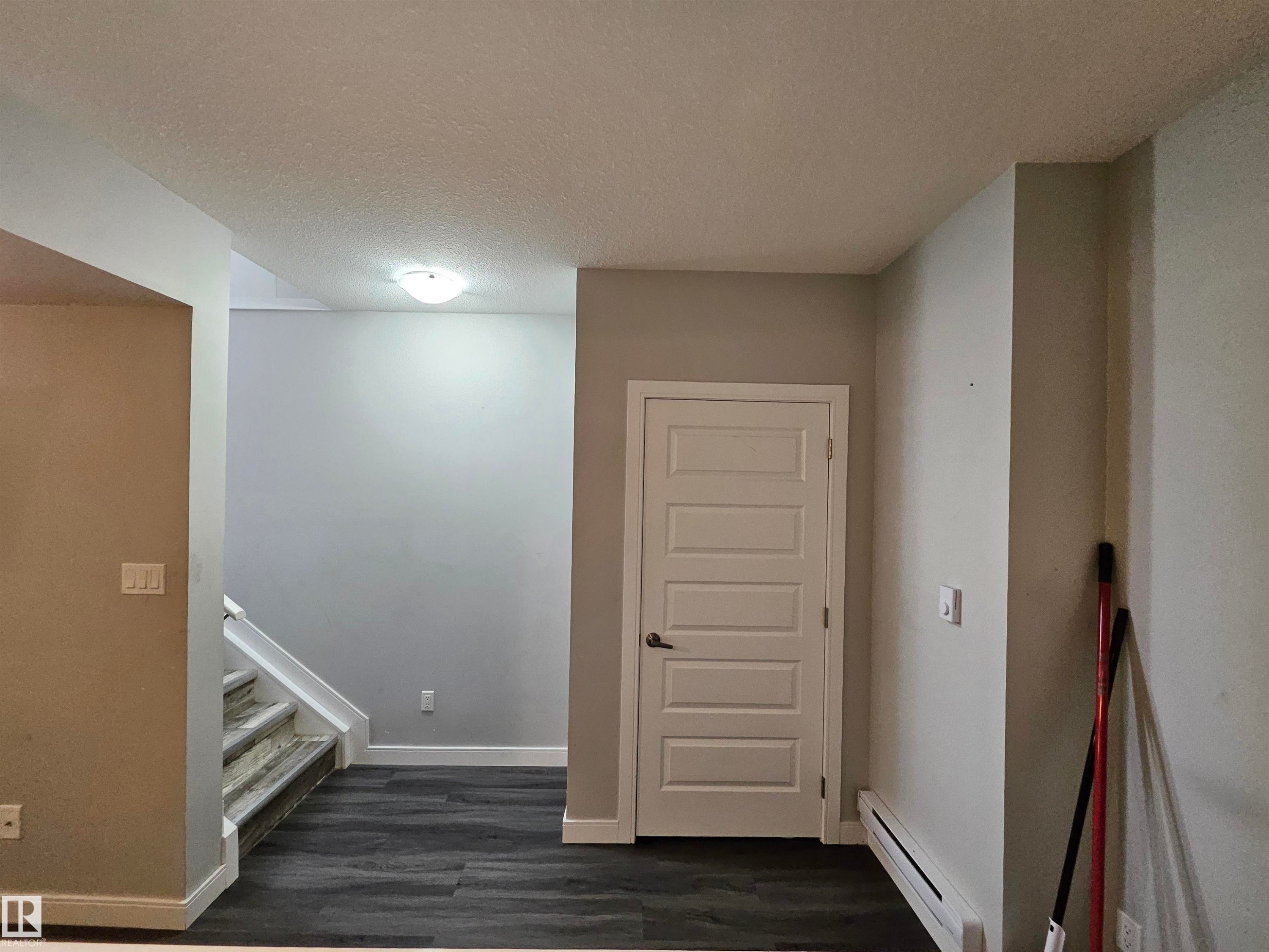 Wood-finish flooring, white paneled door, flush-mount ceiling light, and light gray wall paint - 15212 98 Avenue Nw, Edmonton, AB - Indoor Photo Showing Other Room