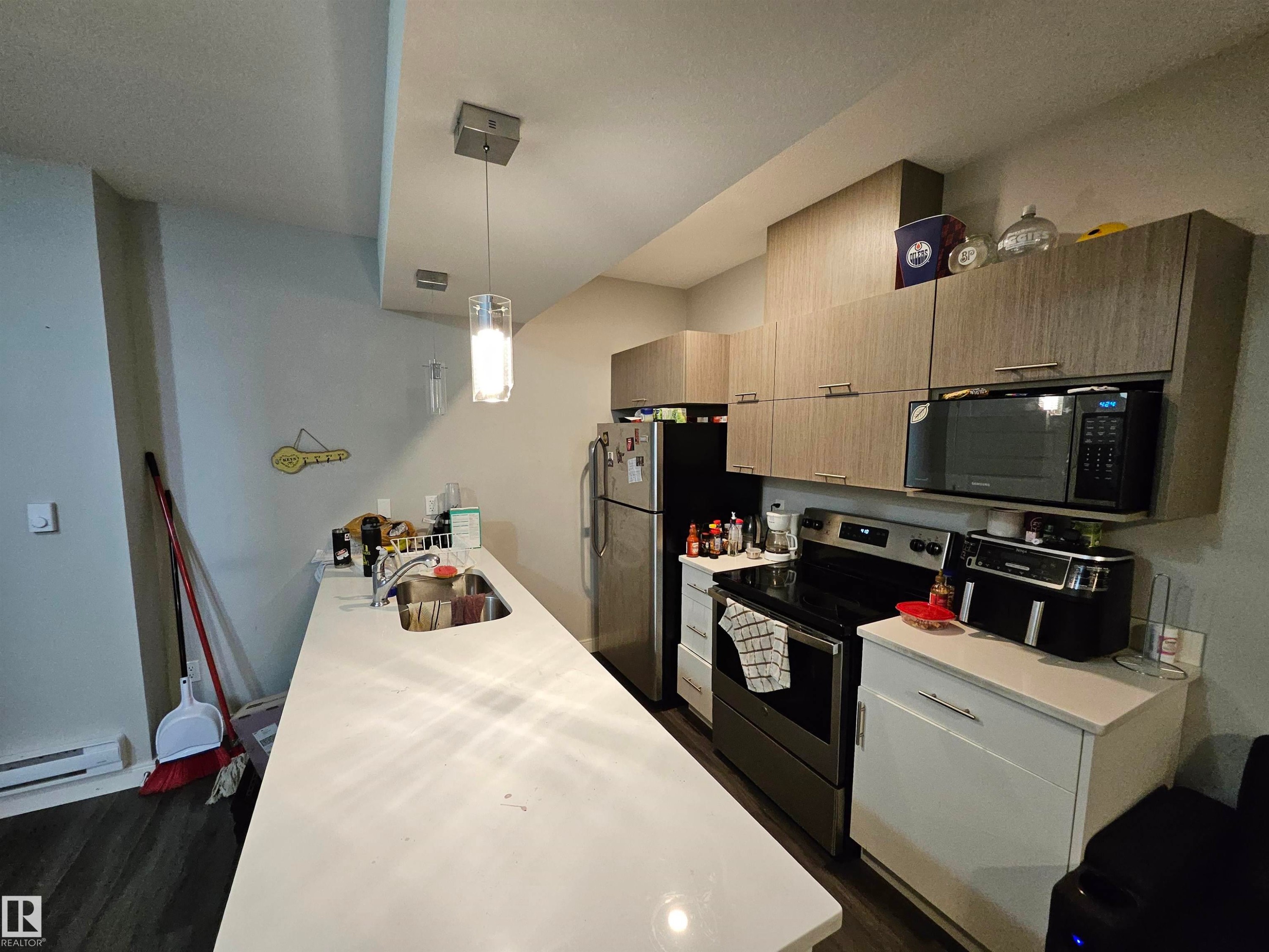 Kitchen featuring wood-finish cabinetry, stainless steel appliances, a built-in microwave, and a white countertop with an integrated sink - 15212 98 Avenue Nw, Edmonton, AB - Indoor Photo Showing Kitchen