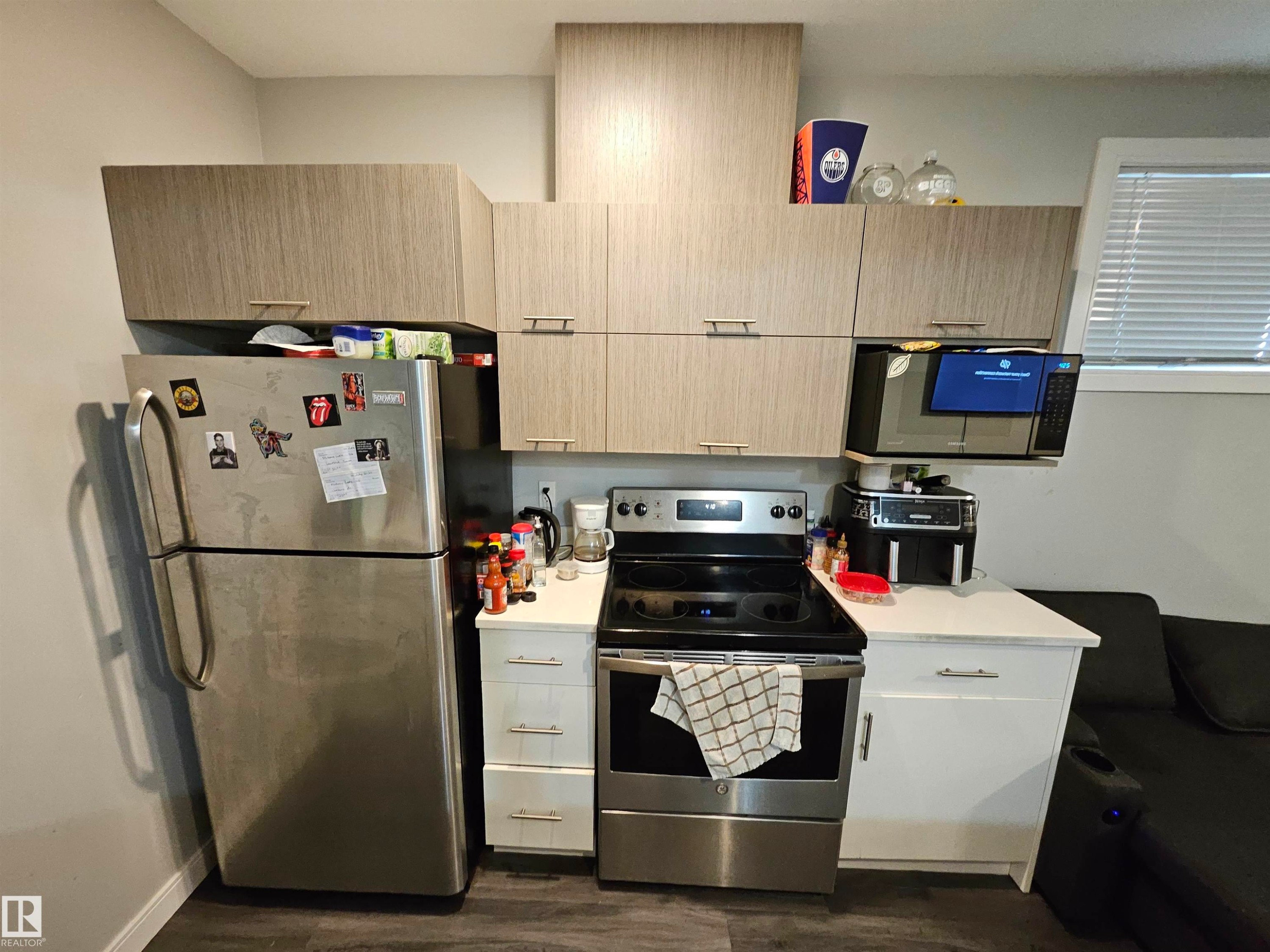 Full-size stainless steel refrigerator, stainless steel electric range, wood-finish cabinetry, white countertops, and a built-in microwave - 15212 98 Avenue Nw, Edmonton, AB - Indoor Photo Showing Other Room