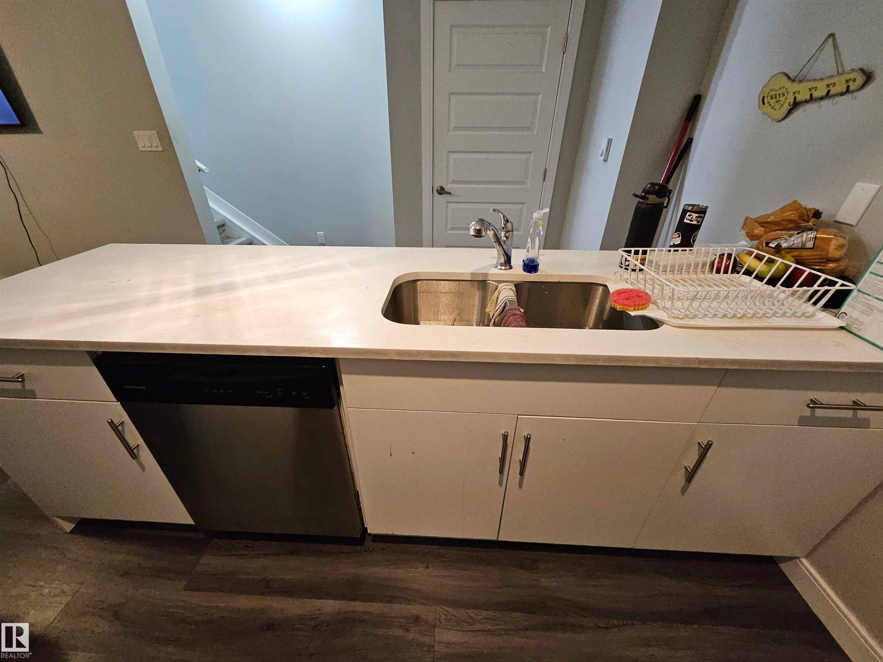 Kitchen island featuring white cabinetry, a stainless steel sink, a stainless steel dishwasher, and a light-toned countertop - 15212 98 Avenue Nw, Edmonton, AB - Indoor Photo Showing Kitchen With Double Sink