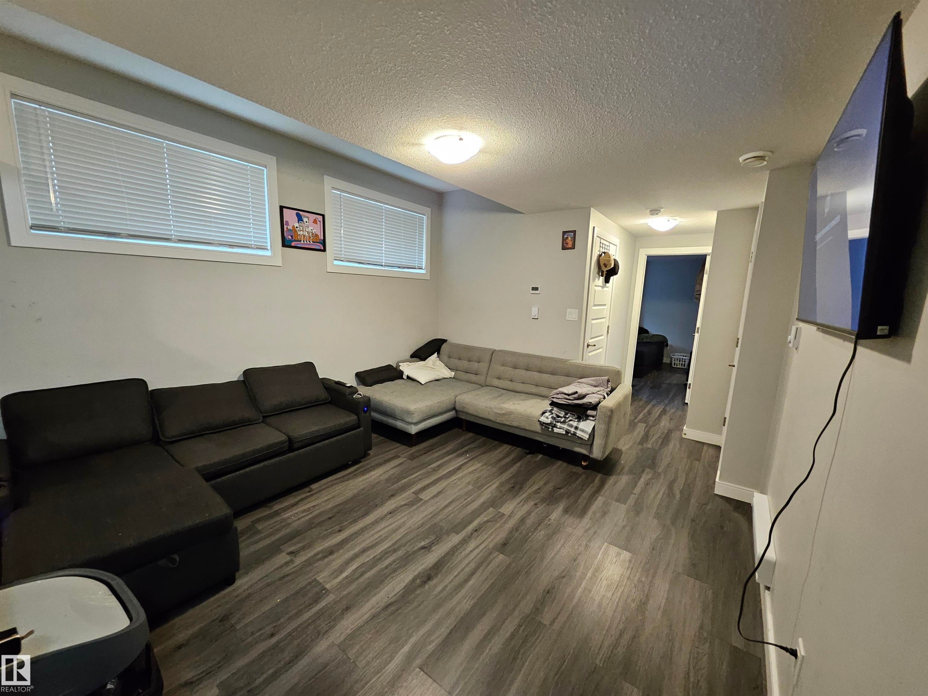 Recessed windows with blinds, wood-finish flooring, and overhead flush mount lighting - 15212 98 Avenue Nw, Edmonton, AB - Indoor Photo Showing Other Room