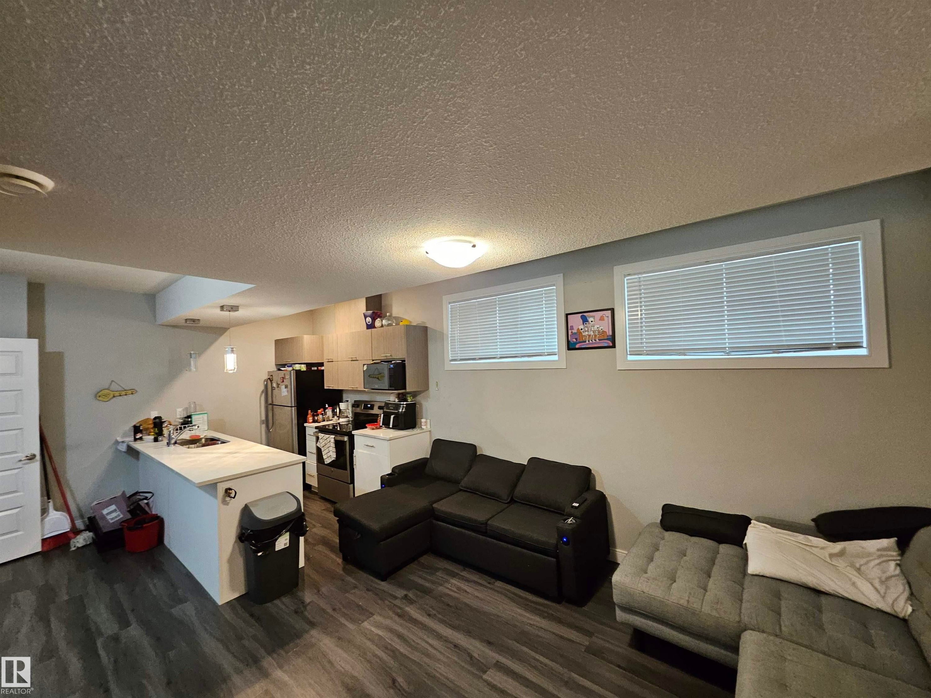 Open-concept living area featuring wood-finish flooring, a kitchen island with a light-colored countertop, and recessed lighting - 15212 98 Avenue Nw, Edmonton, AB - Indoor