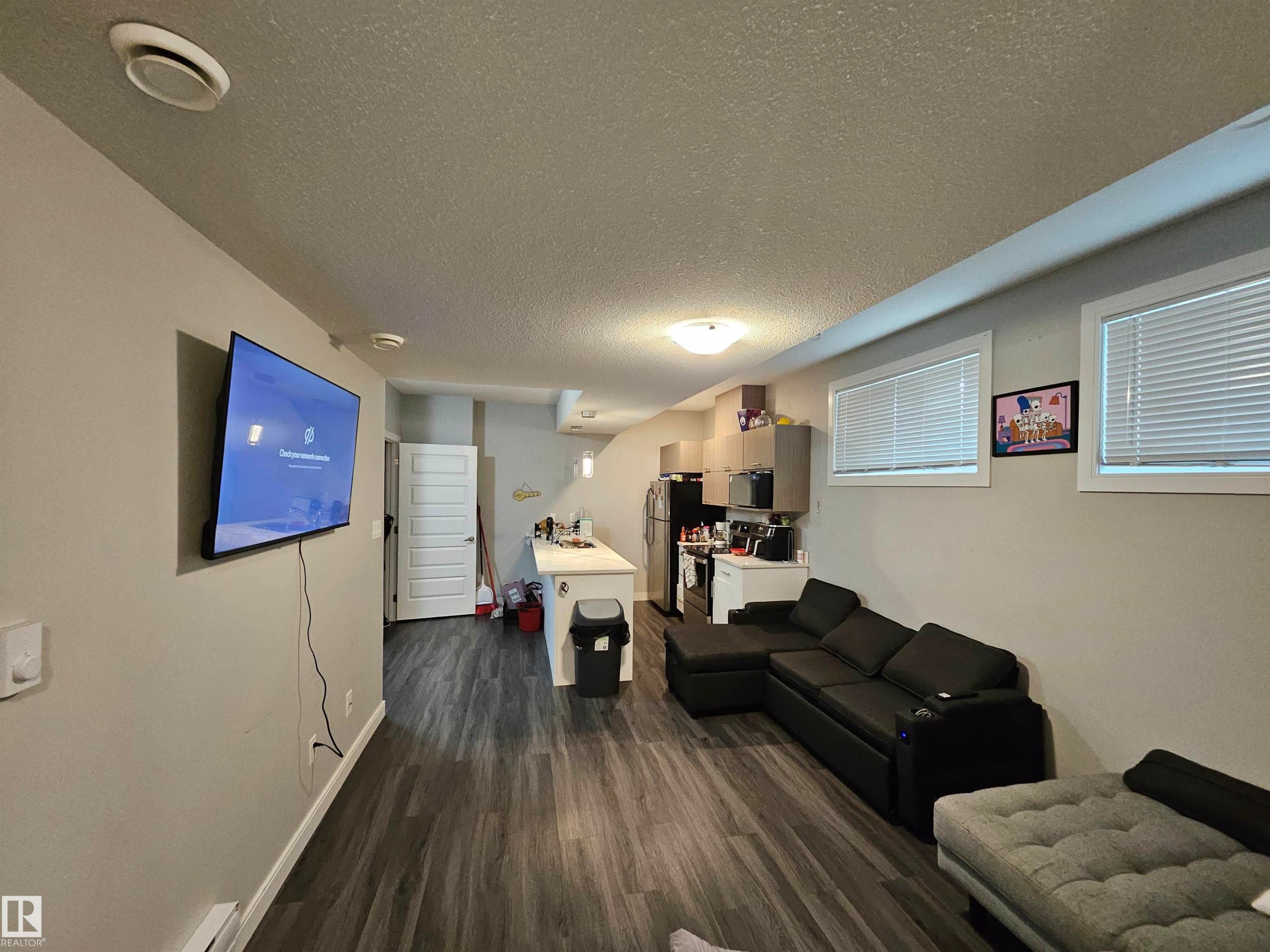 Open-concept living area with dark wood-finish flooring, white trim, and recessed lighting - 15212 98 Avenue Nw, Edmonton, AB - Indoor