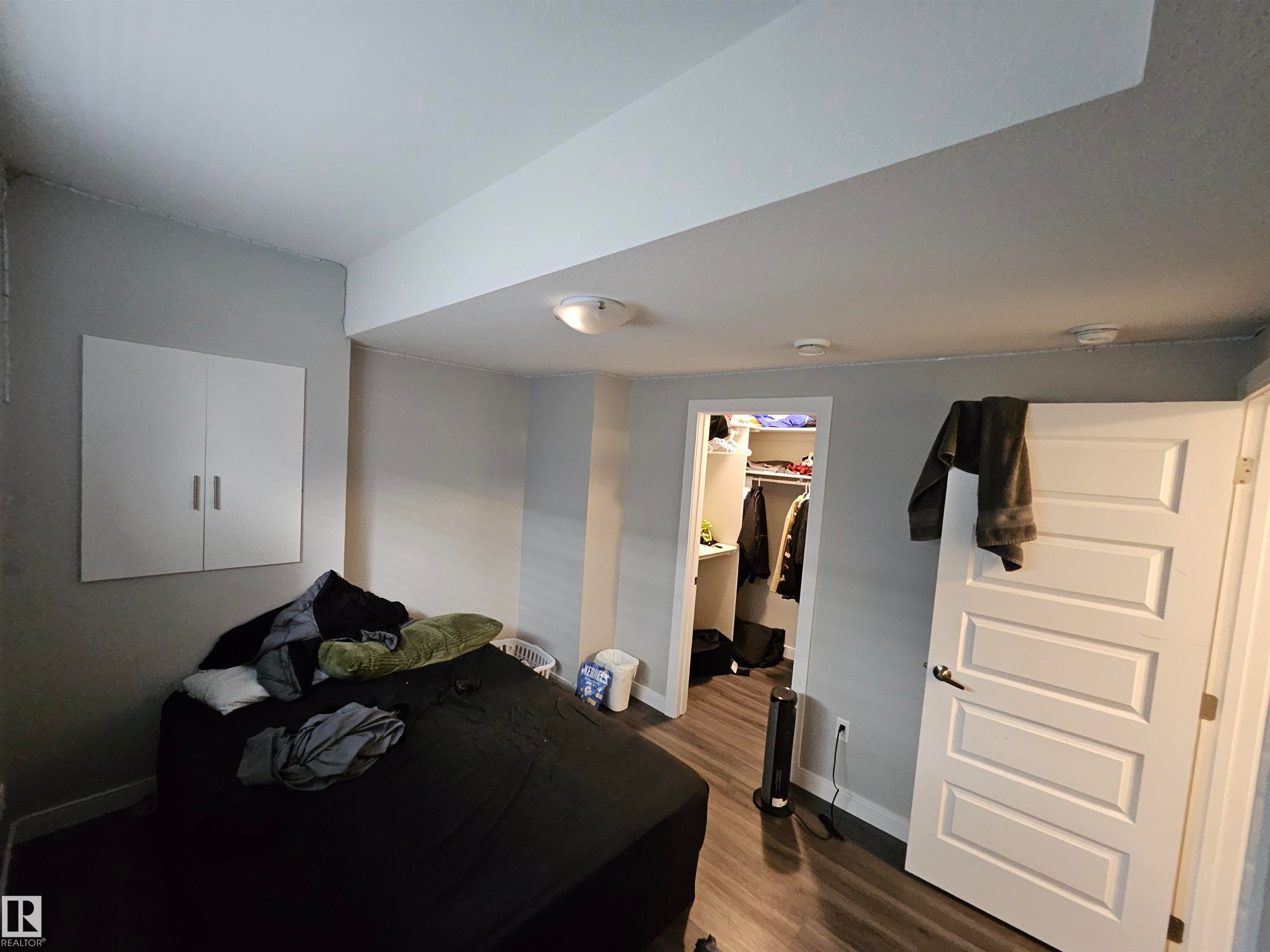 Wood-finish flooring, white panel door, built-in wall cabinet, recessed closet, and overhead lighting - 15212 98 Avenue Nw, Edmonton, AB - Indoor