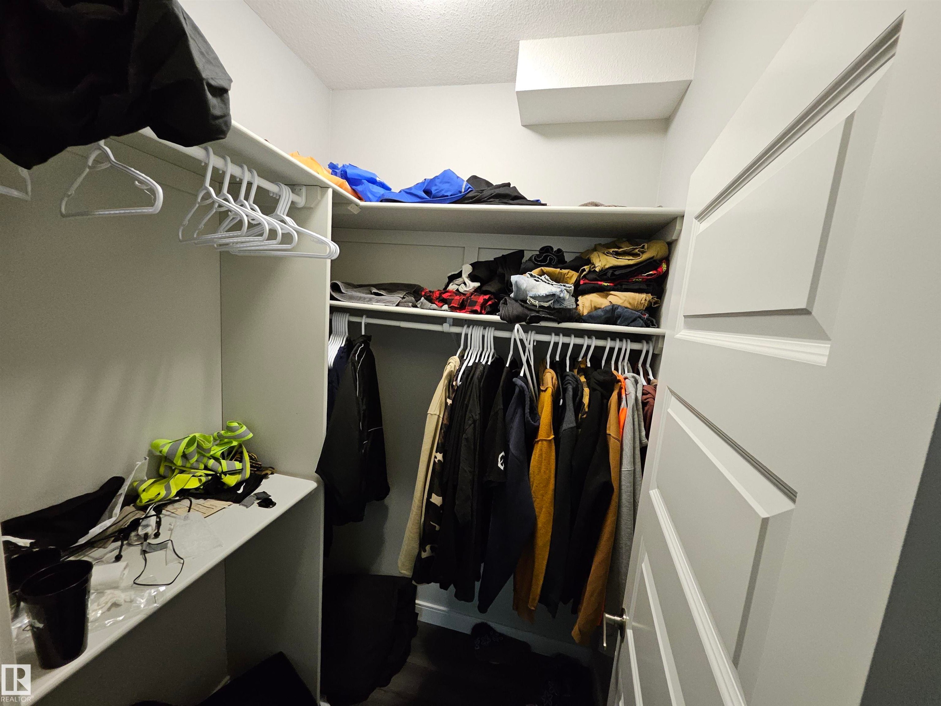Built-in closet shelving, integrated hanging rods, and white paneled door - 15212 98 Avenue Nw, Edmonton, AB - Indoor With Storage