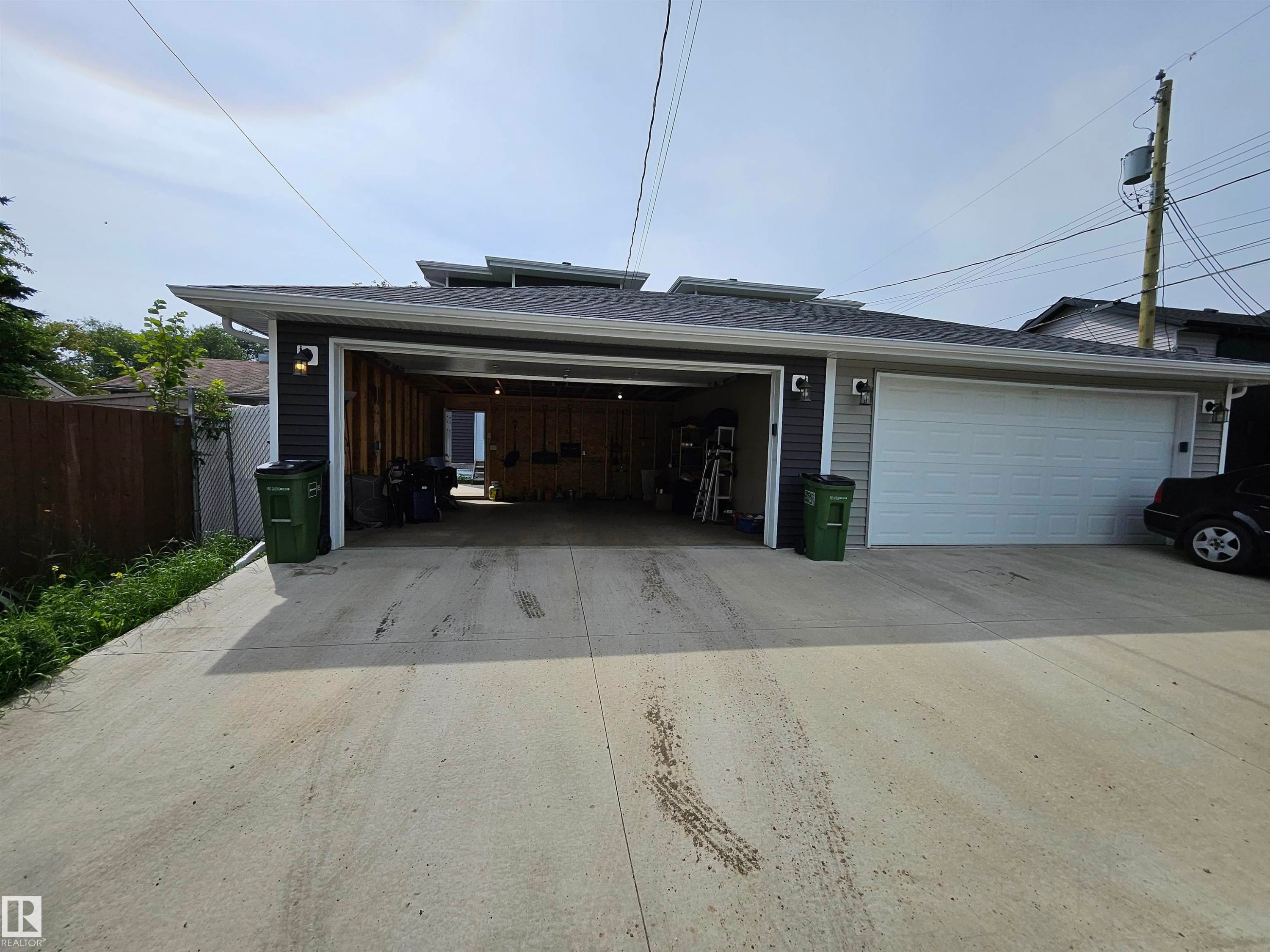 Detached garage with gray siding, a white sectional garage door, and exterior wall sconces - 15212 98 Avenue Nw, Edmonton, AB - Outdoor