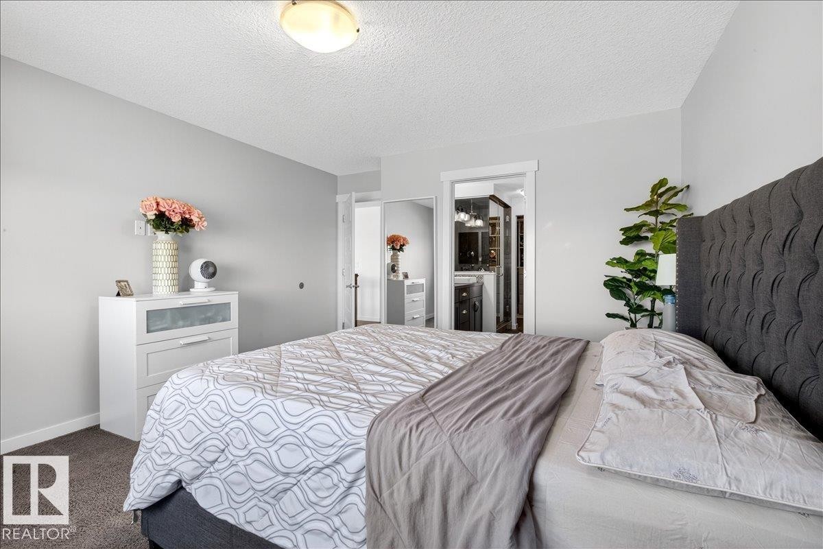 Spacious primary bedroom featuring a charcoal tufted upholstered headboard, carpeted flooring, and abundant natural light from recessed ceiling fixtures - 3936 Claxton Loop Sw, Edmonton, AB - Indoor Photo Showing Bedroom