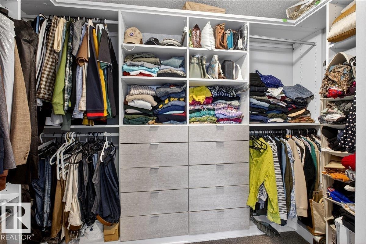Spacious walk-in closet featuring floor-to-ceiling custom cabinetry with multiple shelving sections, organized storage drawers, and dual hanging rods for efficient wardrobe organization - 3936 Claxton Loop Sw, Edmonton, AB - Indoor With Storage