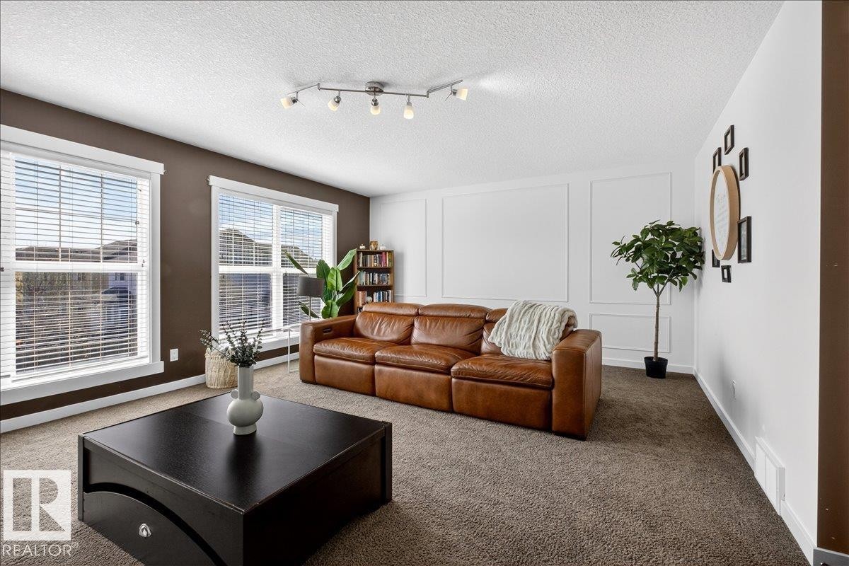 Dual windows with white blinds, track lighting, and wainscoting detail - 3936 Claxton Loop Sw, Edmonton, AB - Indoor Photo Showing Living Room