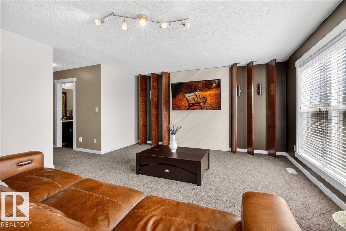 Spacious living room featuring polished concrete flooring, track lighting with multiple fixtures, and floor-to-ceiling windows with integrated blinds - 3936 Claxton Loop Sw, Edmonton, AB - Indoor