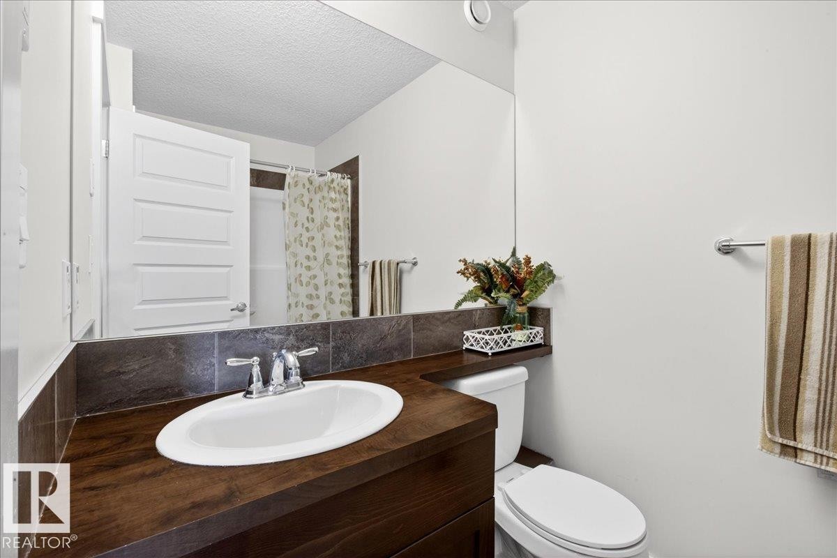 Wood-finish vanity with an integrated oval sink and chrome faucet - 3936 Claxton Loop Sw, Edmonton, AB - Indoor Photo Showing Bathroom