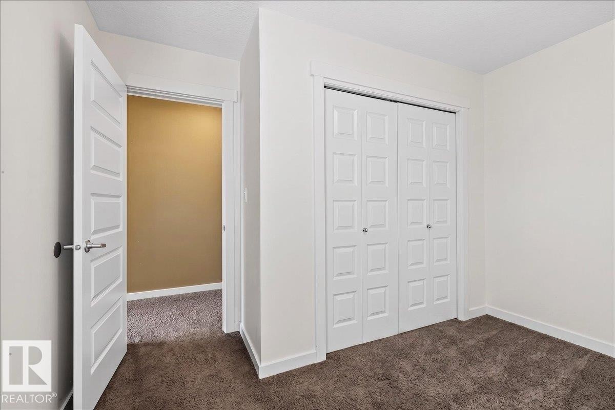 Carpeted flooring, white trim, paneled doors, and bi-fold closet doors - 3936 Claxton Loop Sw, Edmonton, AB - Indoor