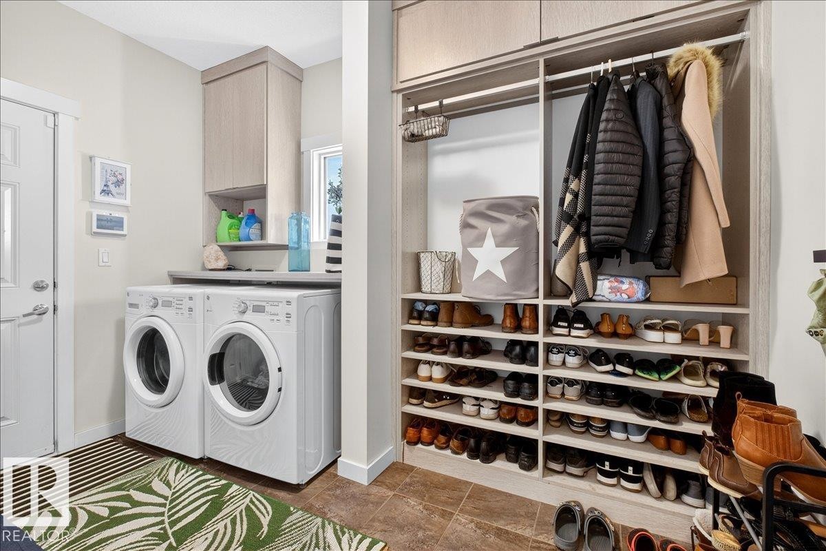 Laundry area featuring stacked front-load machines, a built-in countertop, and an upper cabinet - 3936 Claxton Loop Sw, Edmonton, AB - Indoor Photo Showing Laundry Room