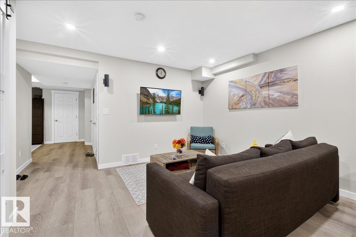 Recessed lighting illuminates the open-concept living space, featuring light wood-finish flooring and neutral wall tones - 3936 Claxton Loop Sw, Edmonton, AB - Indoor