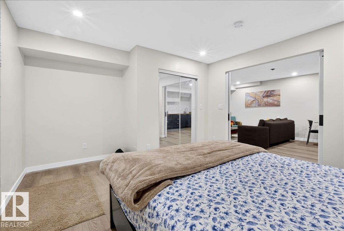 Recessed lighting, wood-finish flooring, sliding glass closet doors, open doorway, and neutral wall tones - 3936 Claxton Loop Sw, Edmonton, AB - Indoor Photo Showing Bedroom