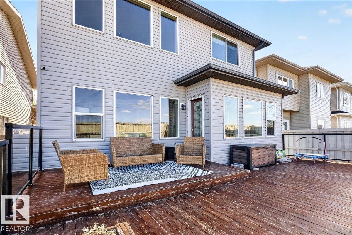 Expansive wood deck with a glass and metal railing, complementing the light gray siding exterior - 3936 Claxton Loop Sw, Edmonton, AB - Outdoor With Exterior